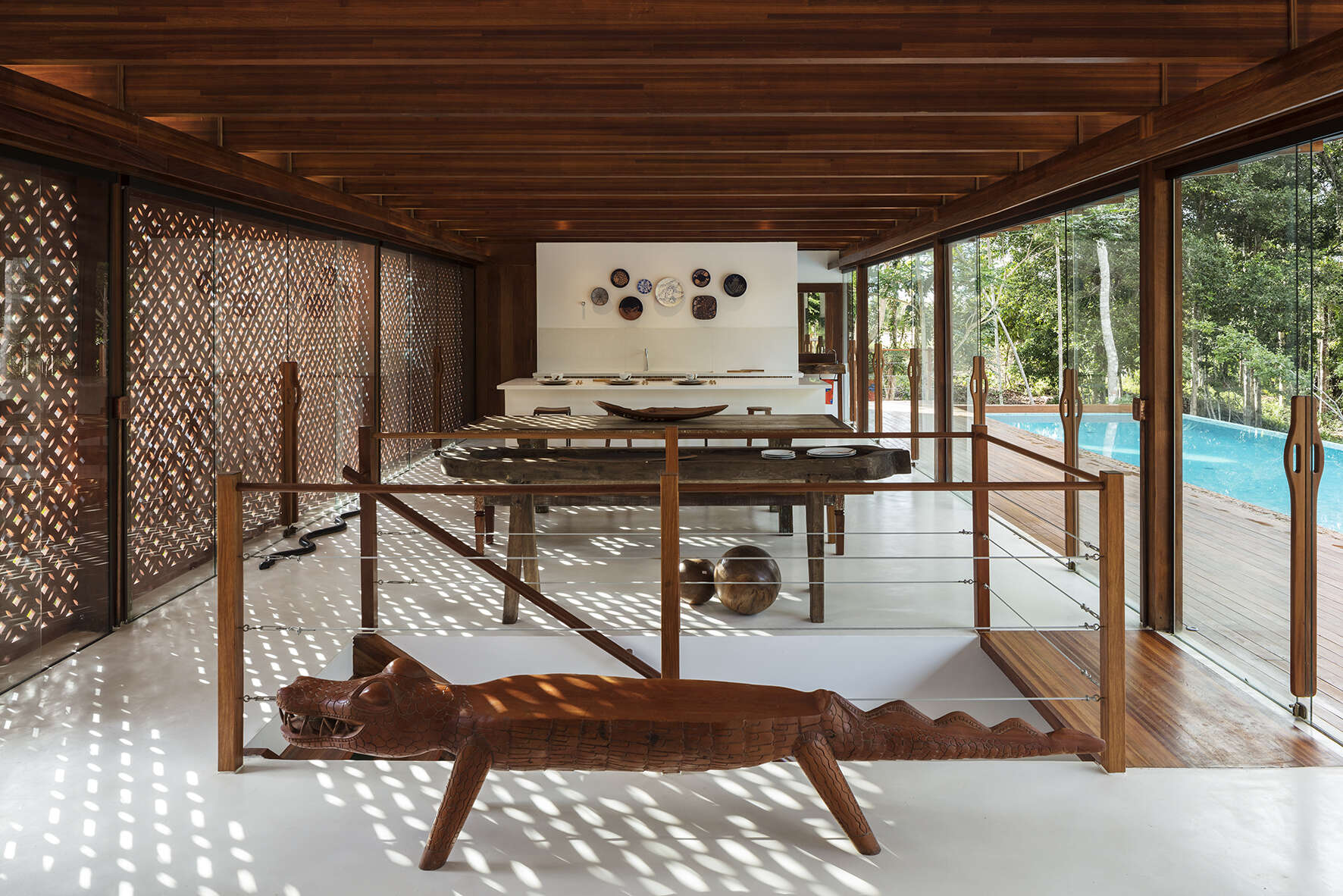 Inside, a 78 foot (24-metre) open-plan living space combines custom furniture, artisan lighting and seamless white cement floors beneath exposed timber beams.