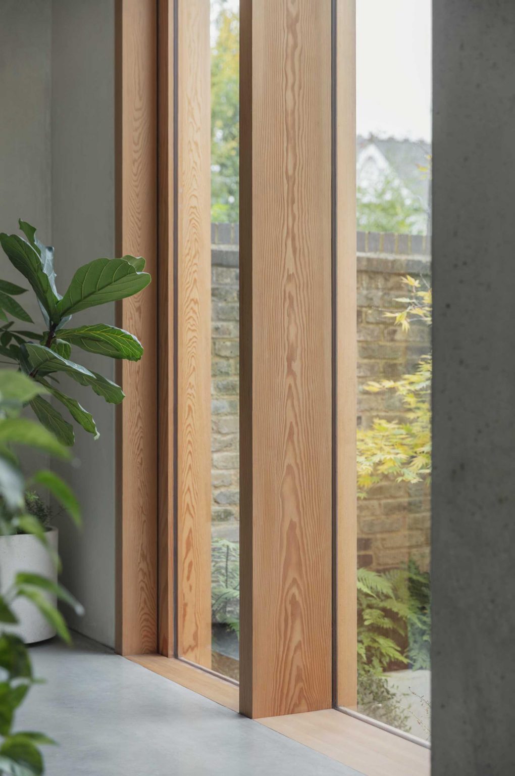 An impressive 11-foot-tall window floods this living room with natural light while framing views of the sheltered courtyard and showcasing the timber extension.