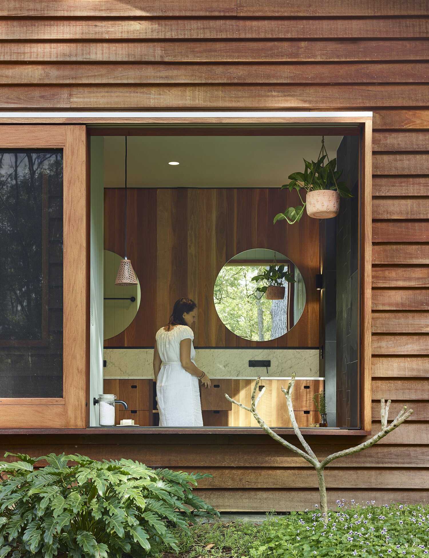 This light-filled bathroom pairs frosted glass with a large picture window overlooking the trees.