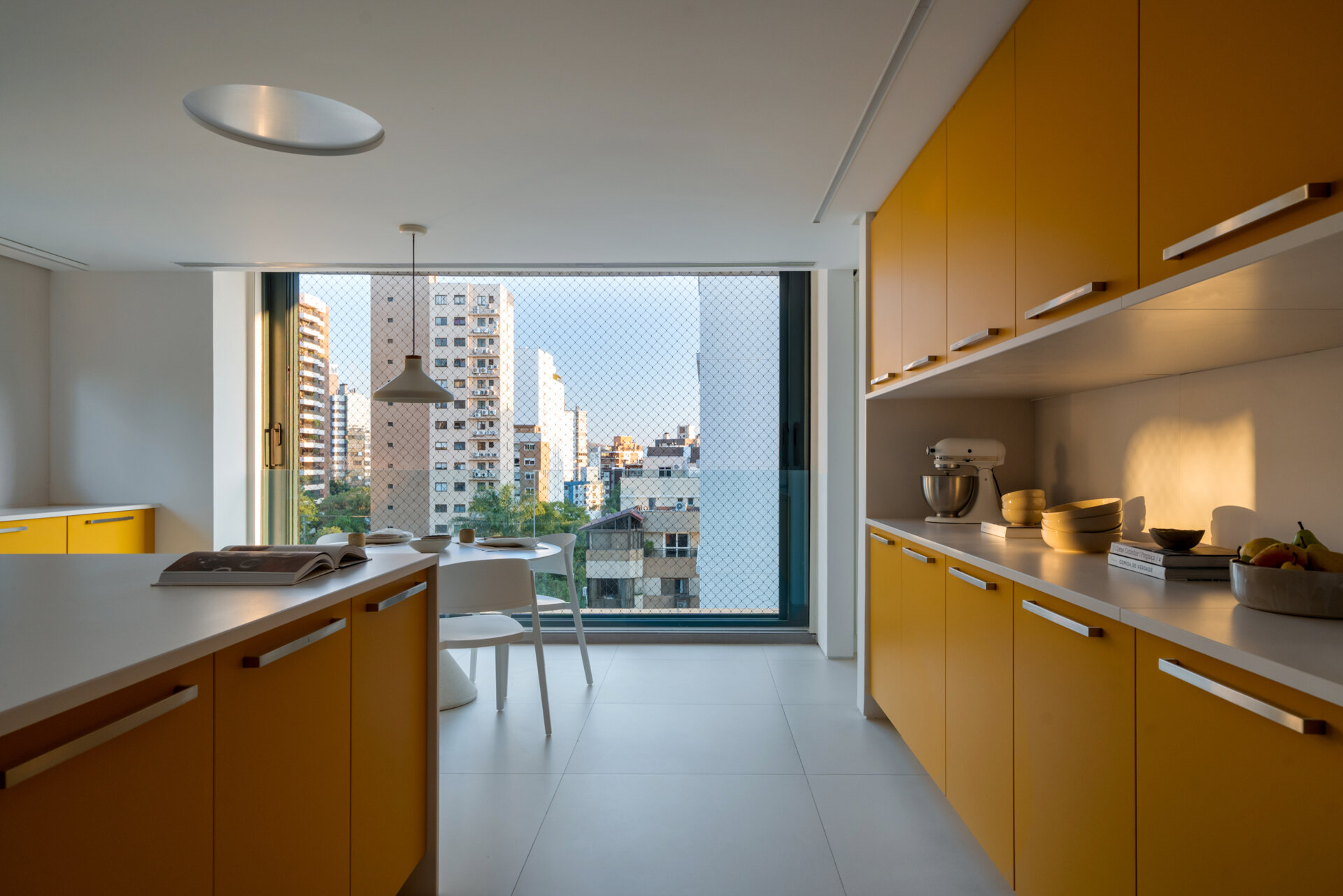 Behind warm timber panels is a cheerful kitchen where pale cabinetry meets bold mustard-yellow storage.