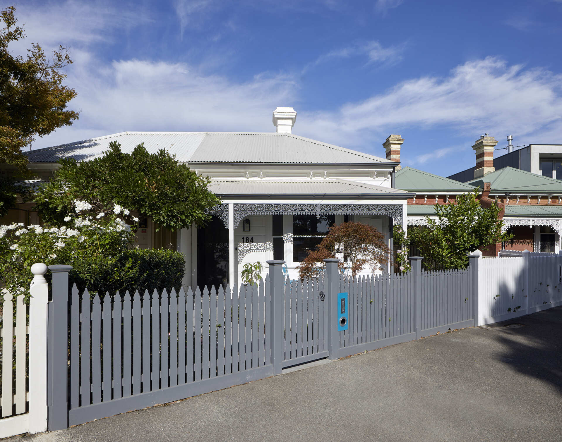 A colorful Victorian workers cottage in Port Melbourne gets an eye-catching street makeover with painted iron lacework and a refreshed heritage facade.