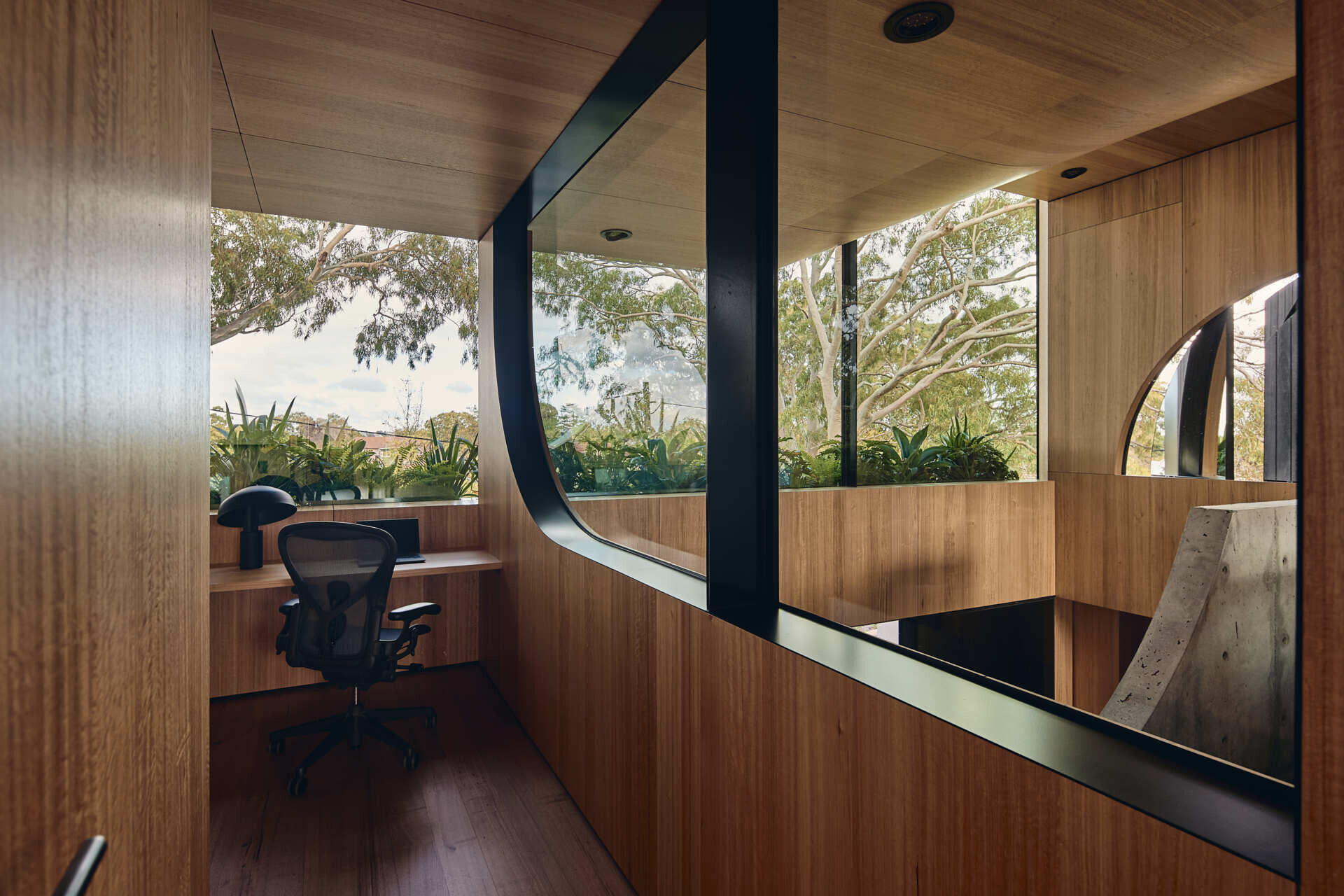 The primary suite at Babylonia features a cocoon-like bedroom, timber-lined ceilings, natural stone and views toward the garden beneath the eucalypt canopy.