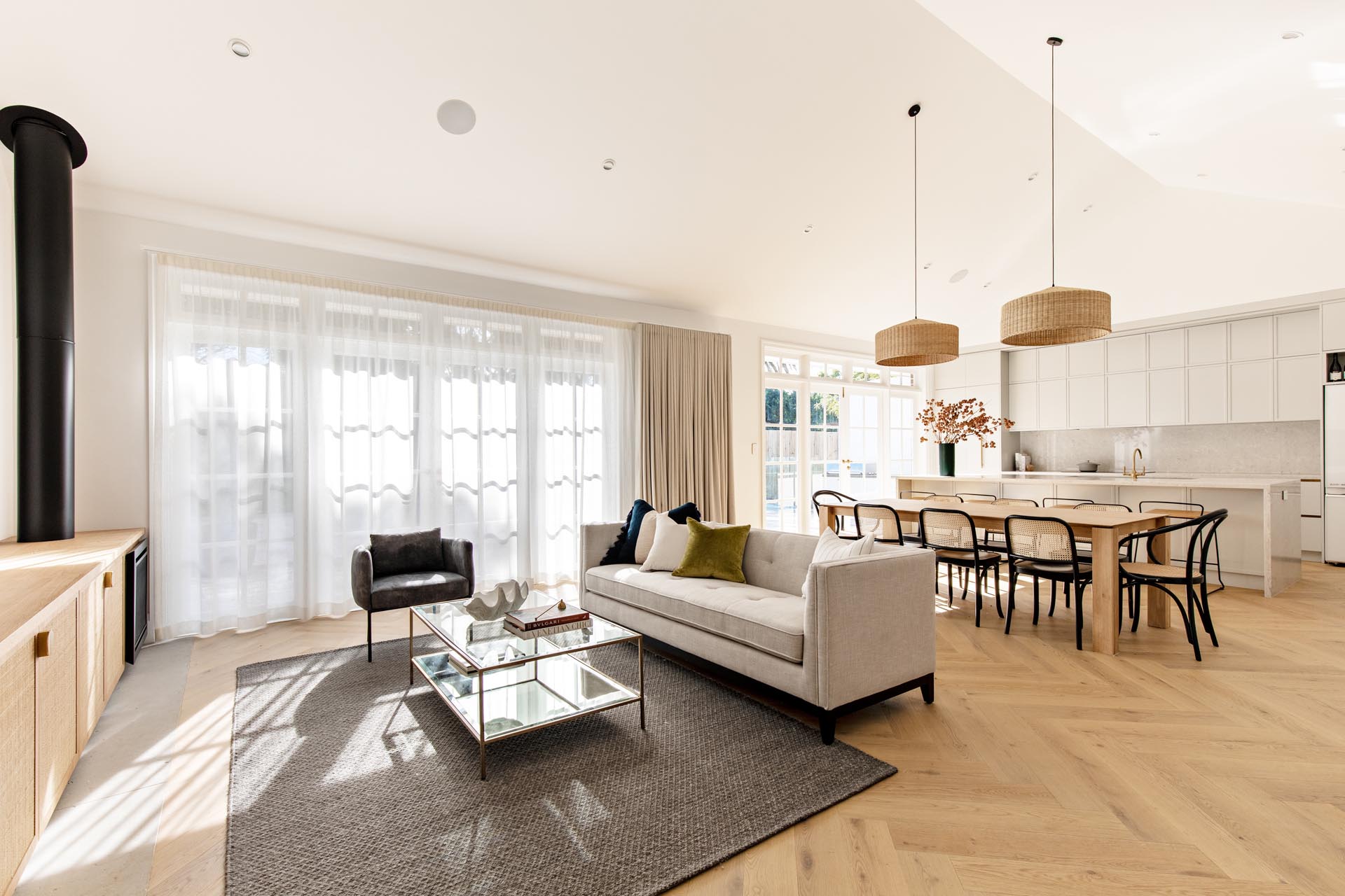 Take a closer look at this Concord living room, featuring custom rattan and oak joinery, a black gas fireplace, open shelving, aged brass details and oak herringbone floors.