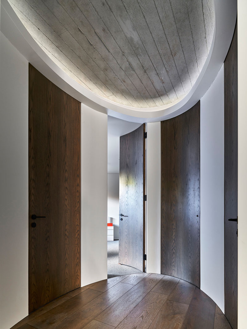 The first-floor oval hallway at The Books House features custom full-height curved doors leading to the bedrooms and bathrooms.