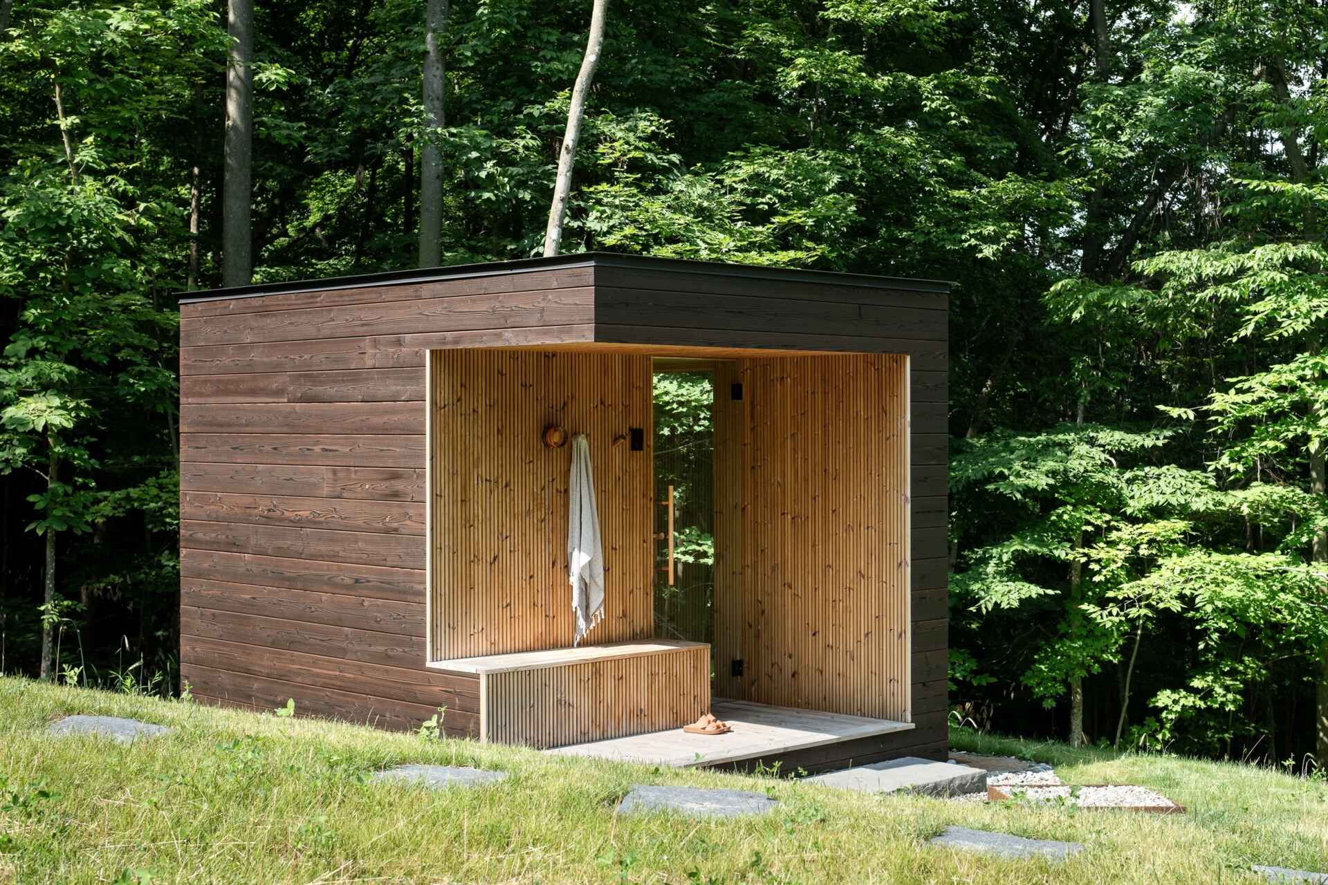 See the detached sauna at the Milo House in Cornwall, Vermont, clad in the same dark yakisugi siding as the main residence and garden shed.