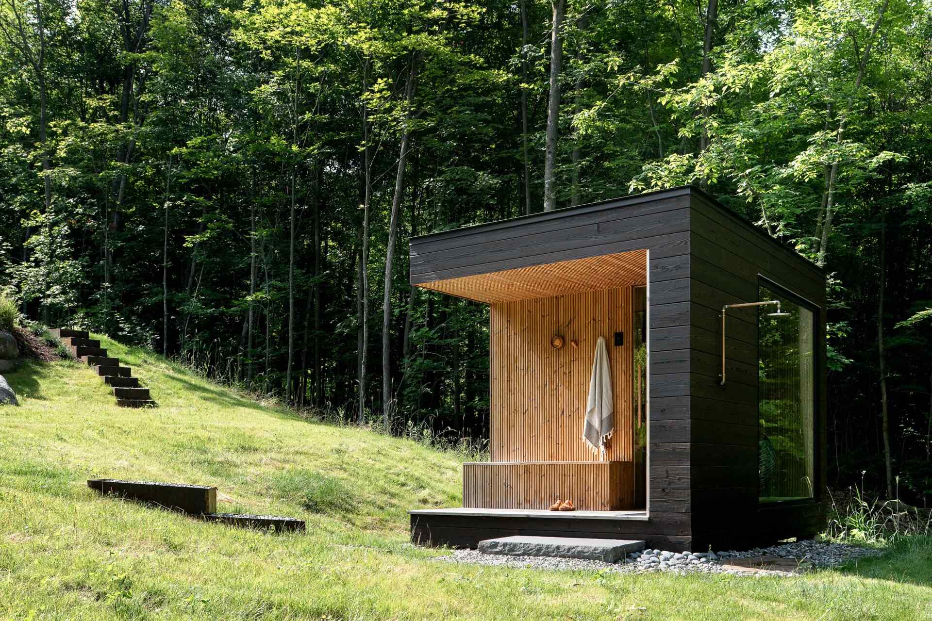 See the detached sauna at the Milo House in Cornwall, Vermont, clad in the same dark yakisugi siding as the main residence and garden shed.