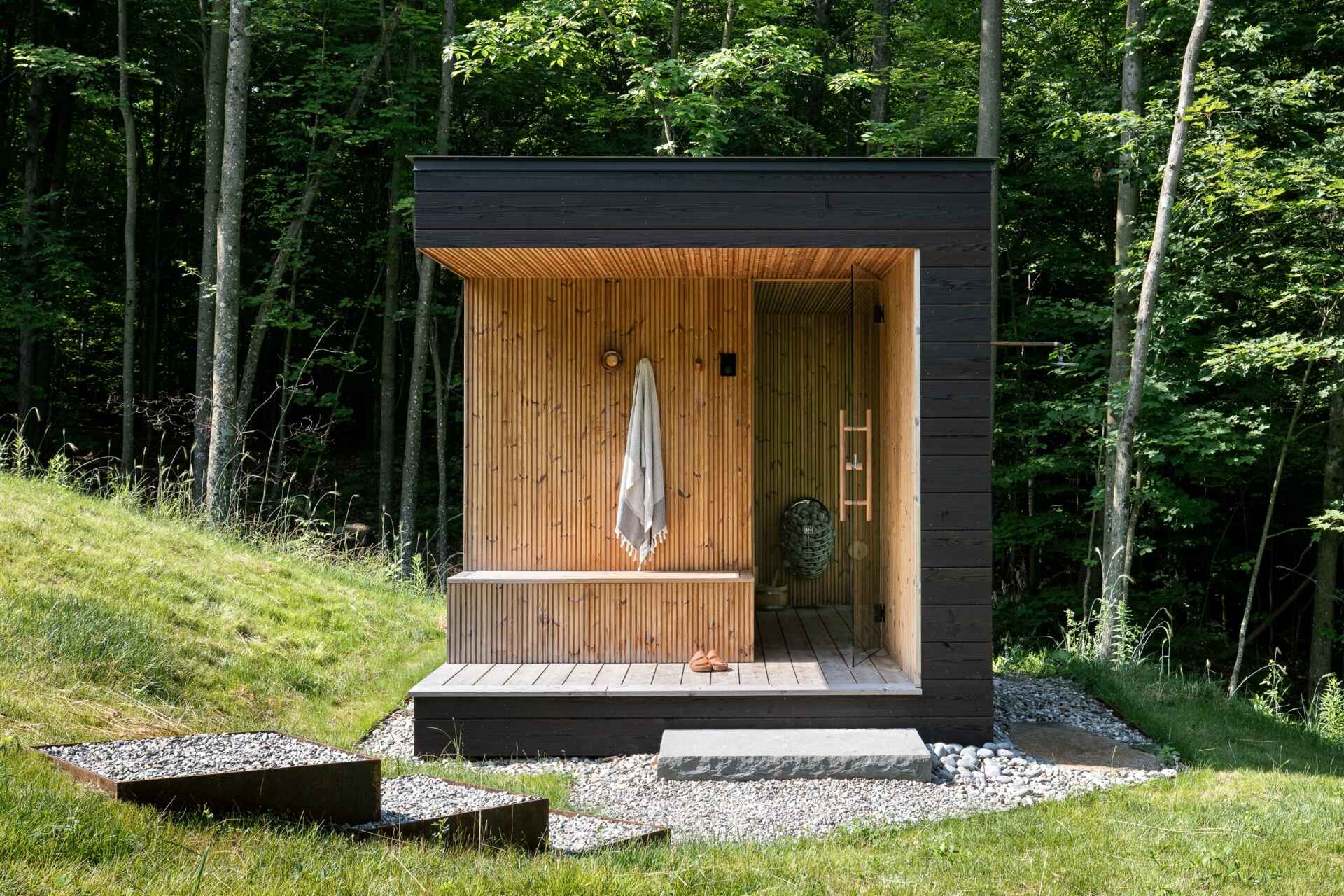 See the detached sauna at the Milo House in Cornwall, Vermont, clad in the same dark yakisugi siding as the main residence and garden shed.