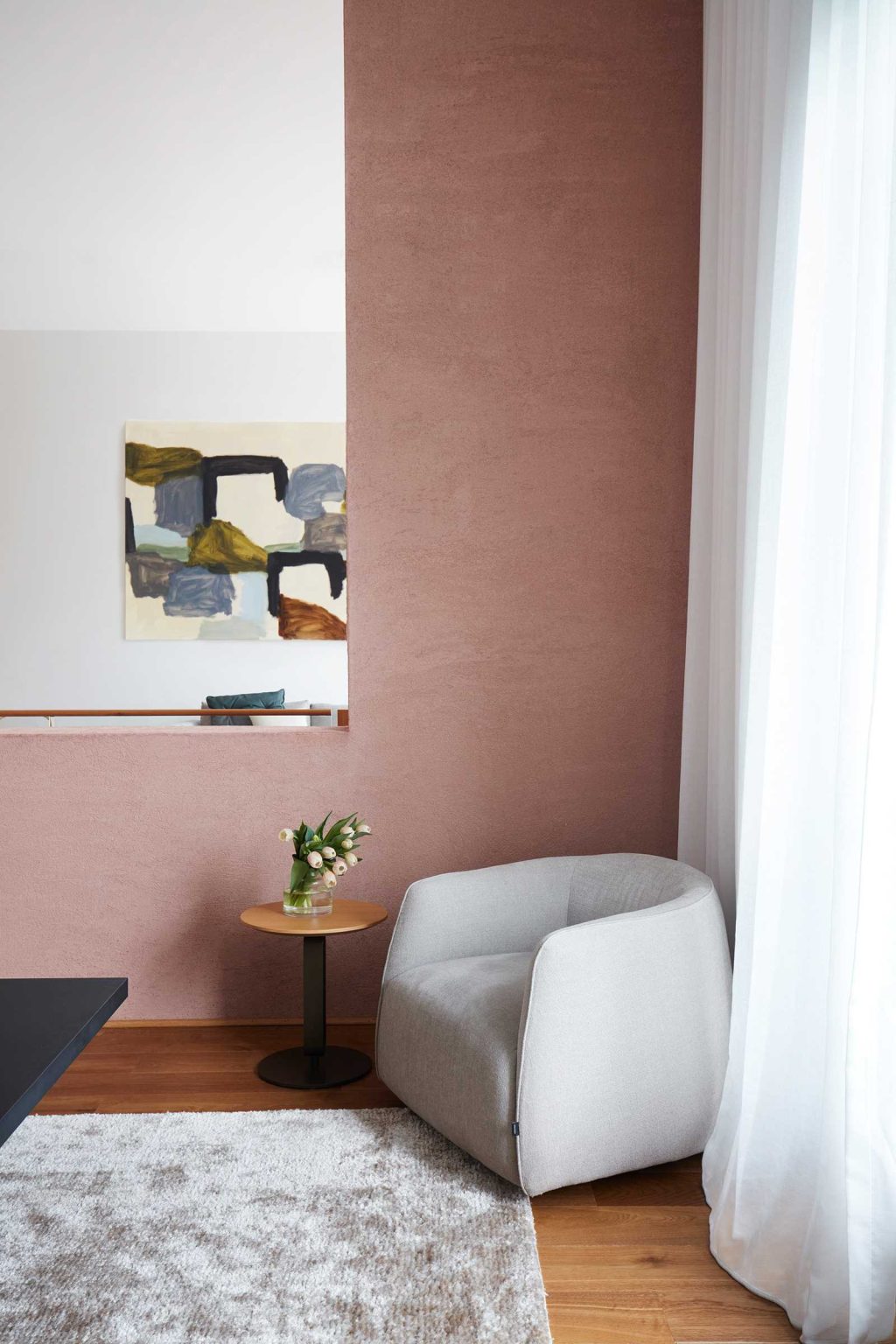 Earth-Ship's double-height dining room features a long horizontal light above the table, plus a single chair and side table tucked into one corner.