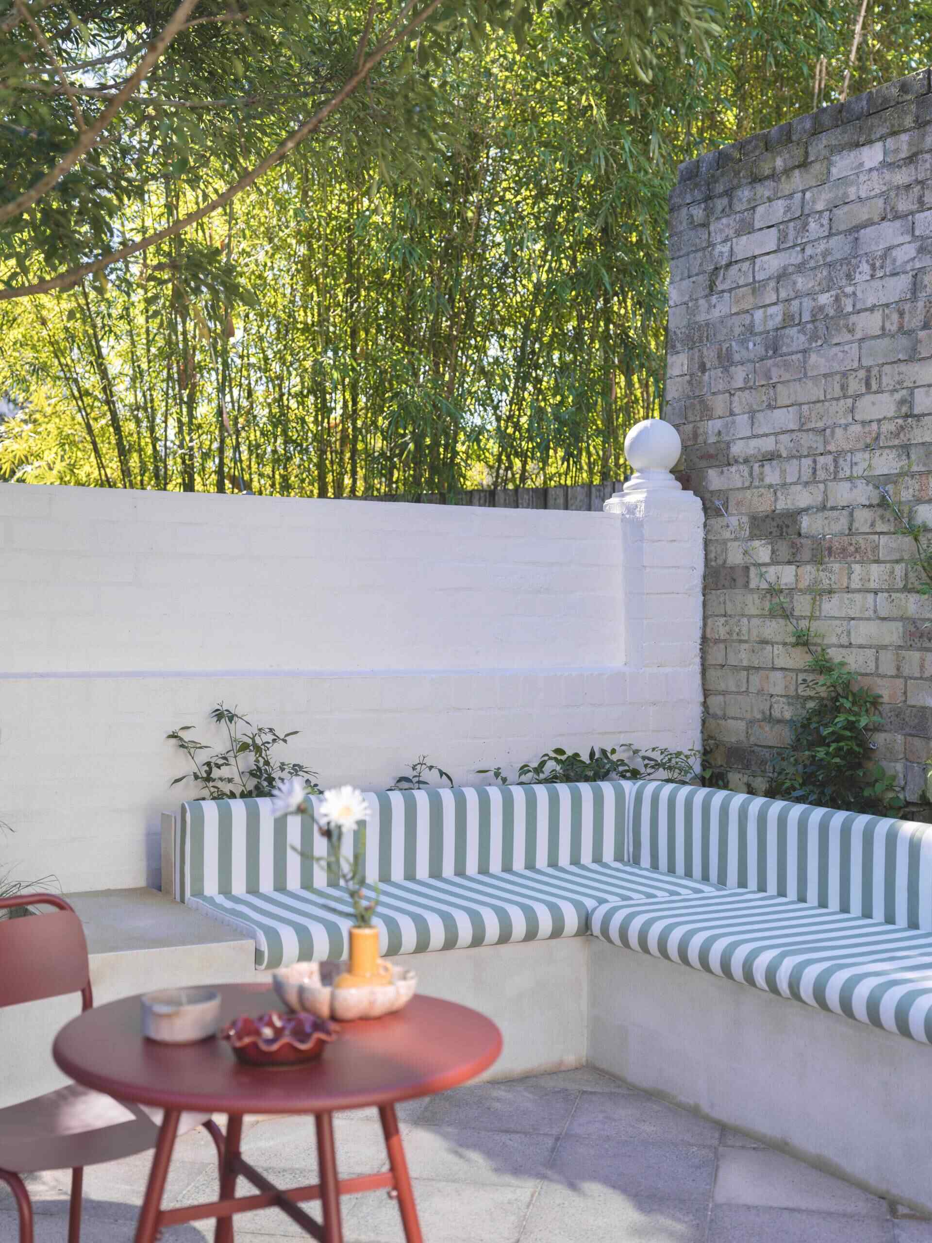 Built-in banquette seating tucked beneath mature trees creates the perfect shaded spot for relaxing or entertaining outdoors.