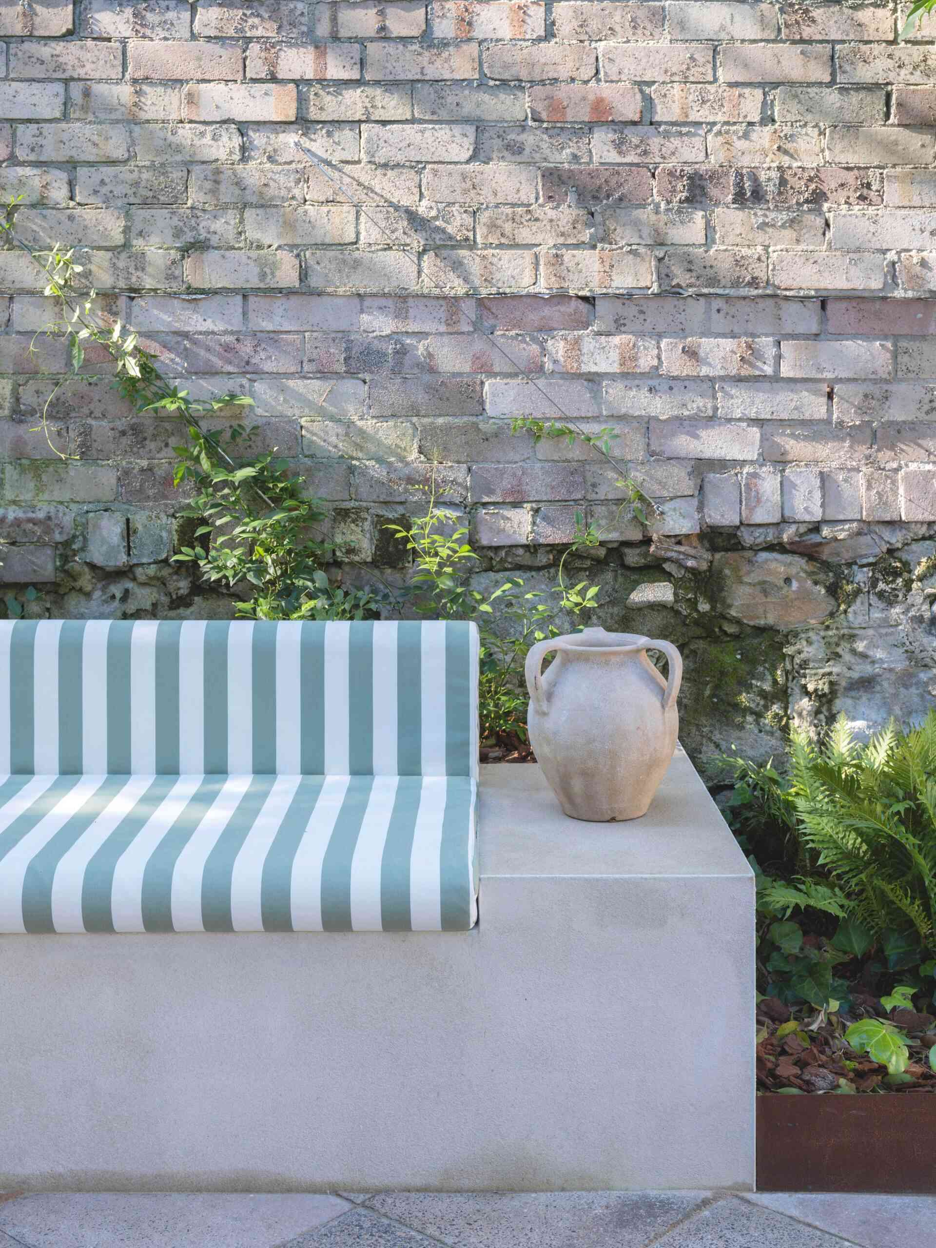 Built-in banquette seating tucked beneath mature trees creates the perfect shaded spot for relaxing or entertaining outdoors.