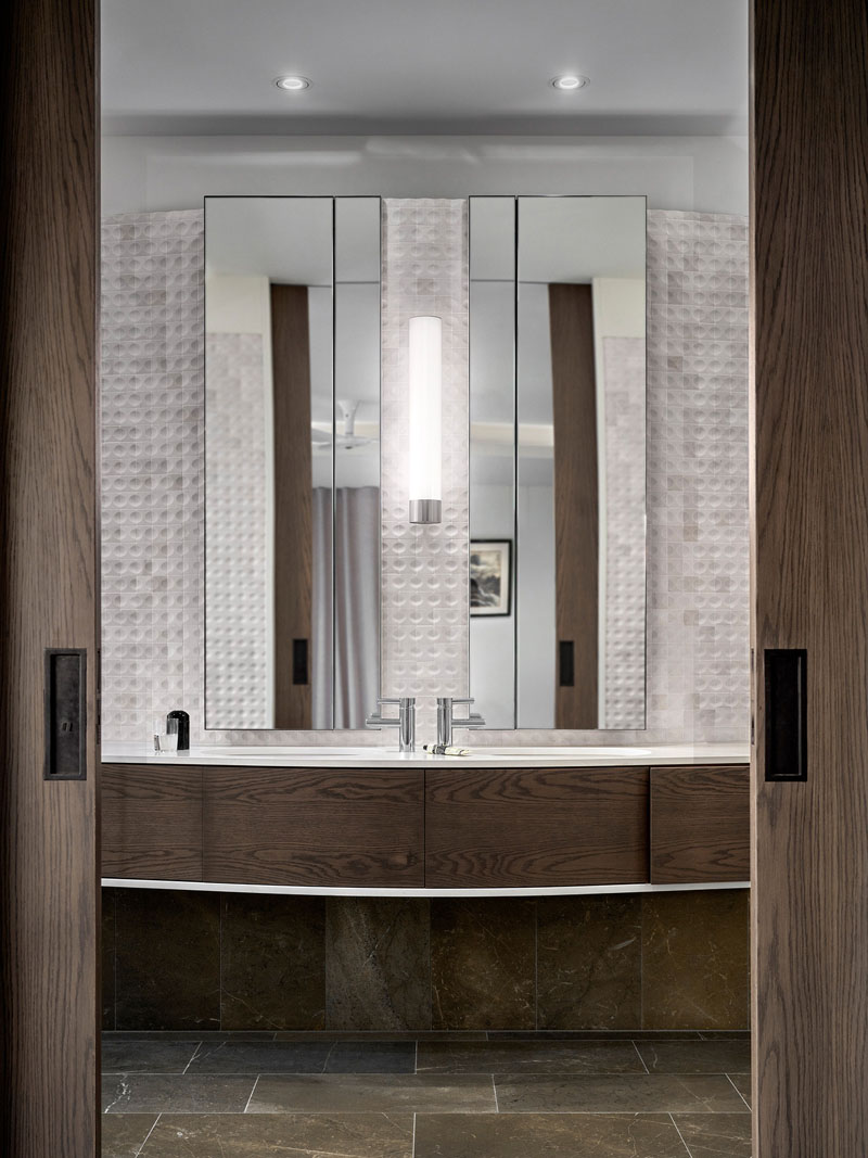 A custom timber vanity contrasts with white marble mosaic tiles in one of the bathrooms at The Books House in Sydney.