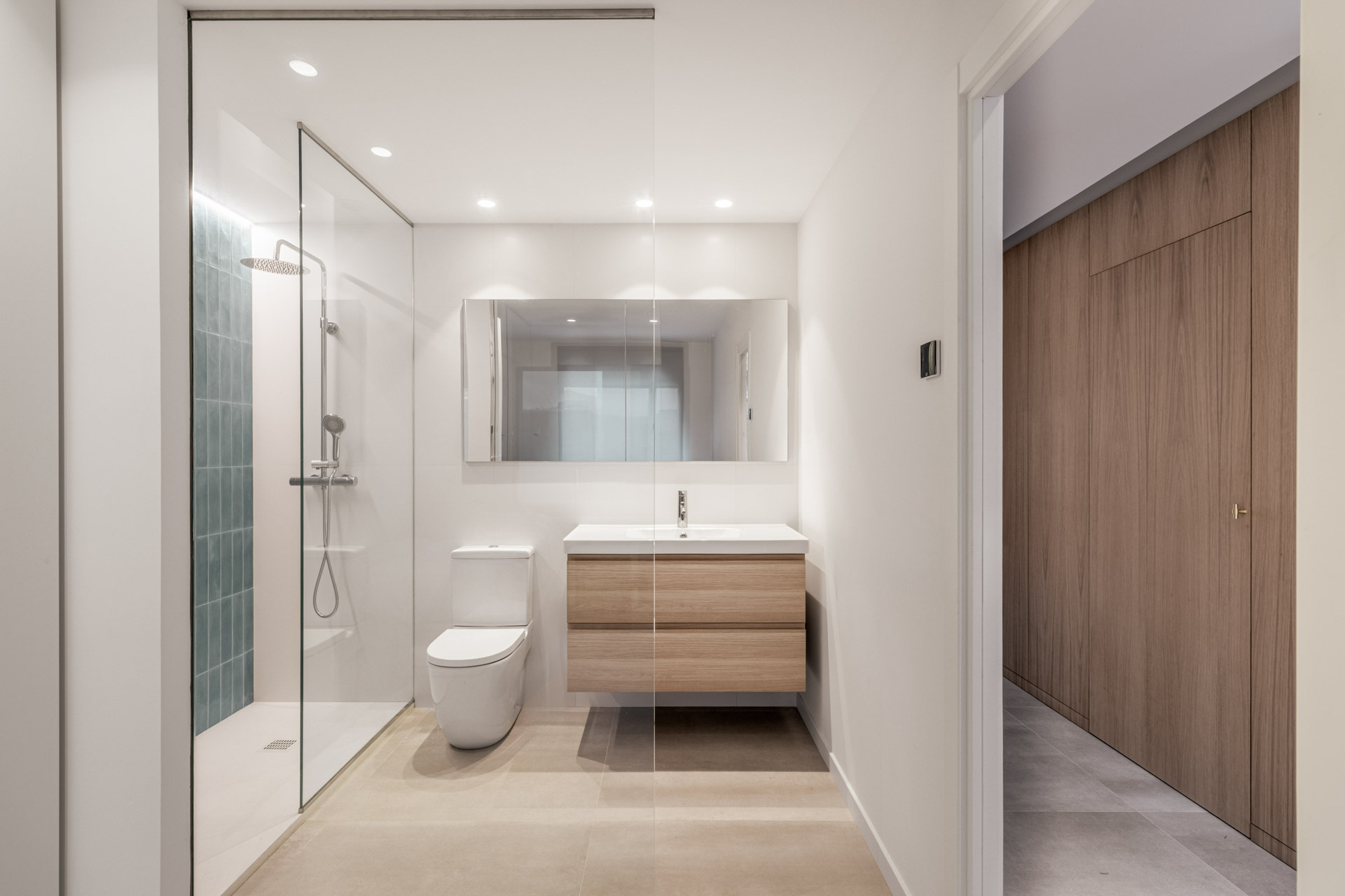 Turquoise tiles, light timber and a glass shower screen give one of the bathrooms in this Madrid home a fresh material palette beside the original staircase.