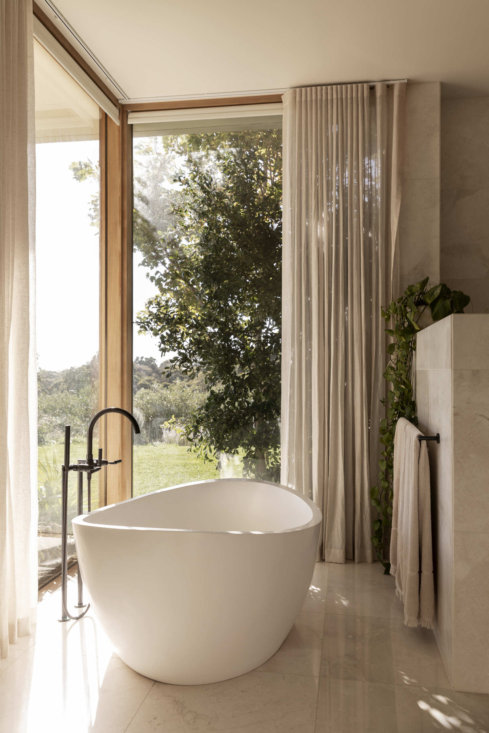 Explore the bathrooms at Smoke Bush House, where natural textures and soft light continue the home's understated interior palette and relaxed architectural language.
