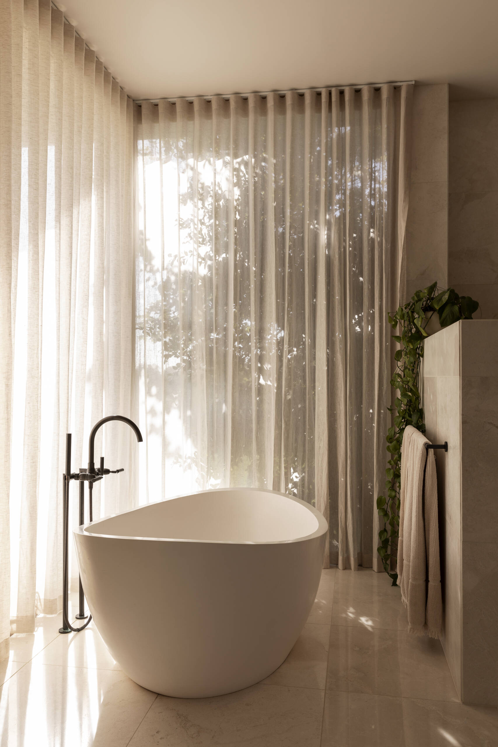 Explore the bathrooms at Smoke Bush House, where natural textures and soft light continue the home's understated interior palette and relaxed architectural language.