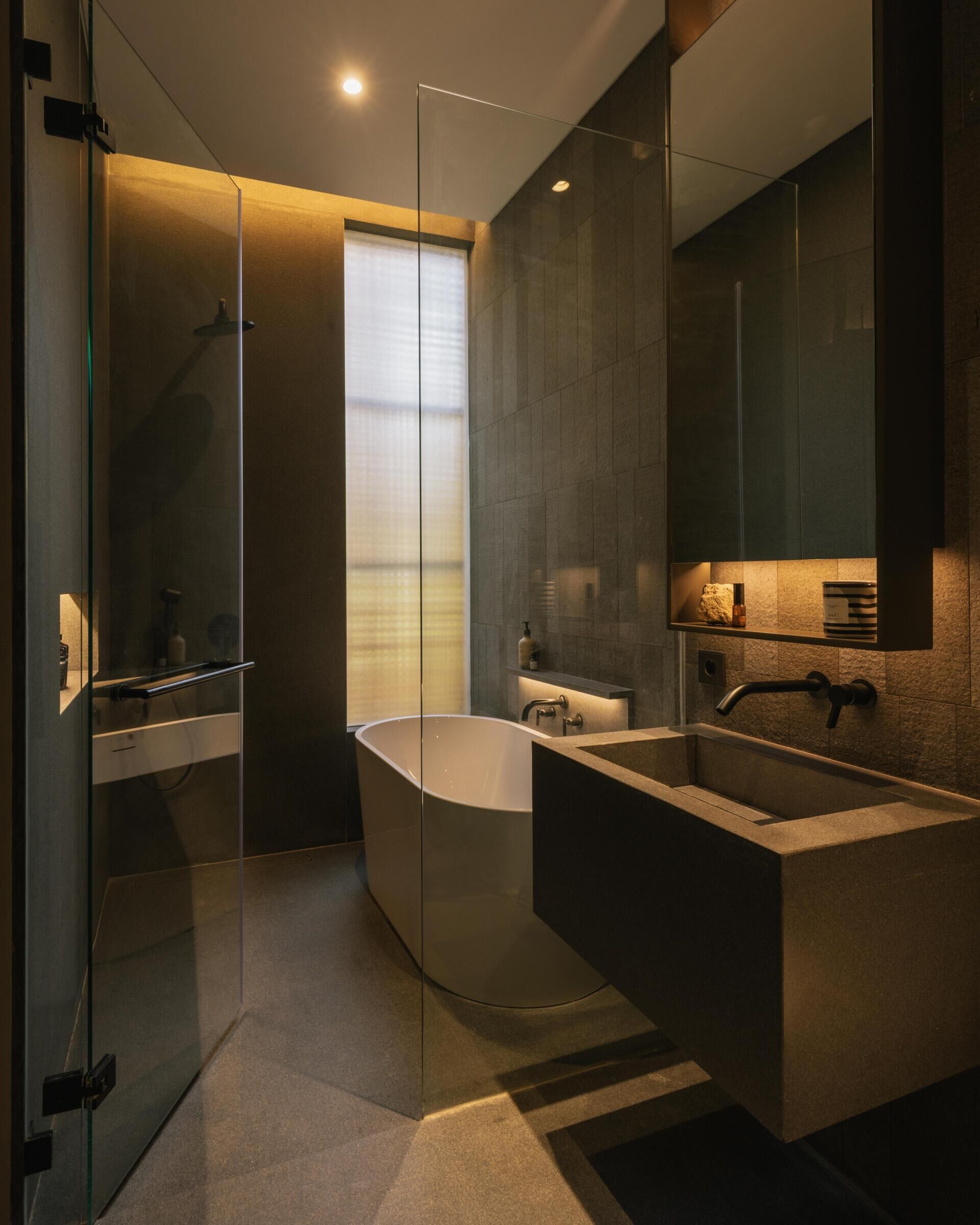A modern bathroom with high ceilings, dark walls, tall window, and a floating vanity.