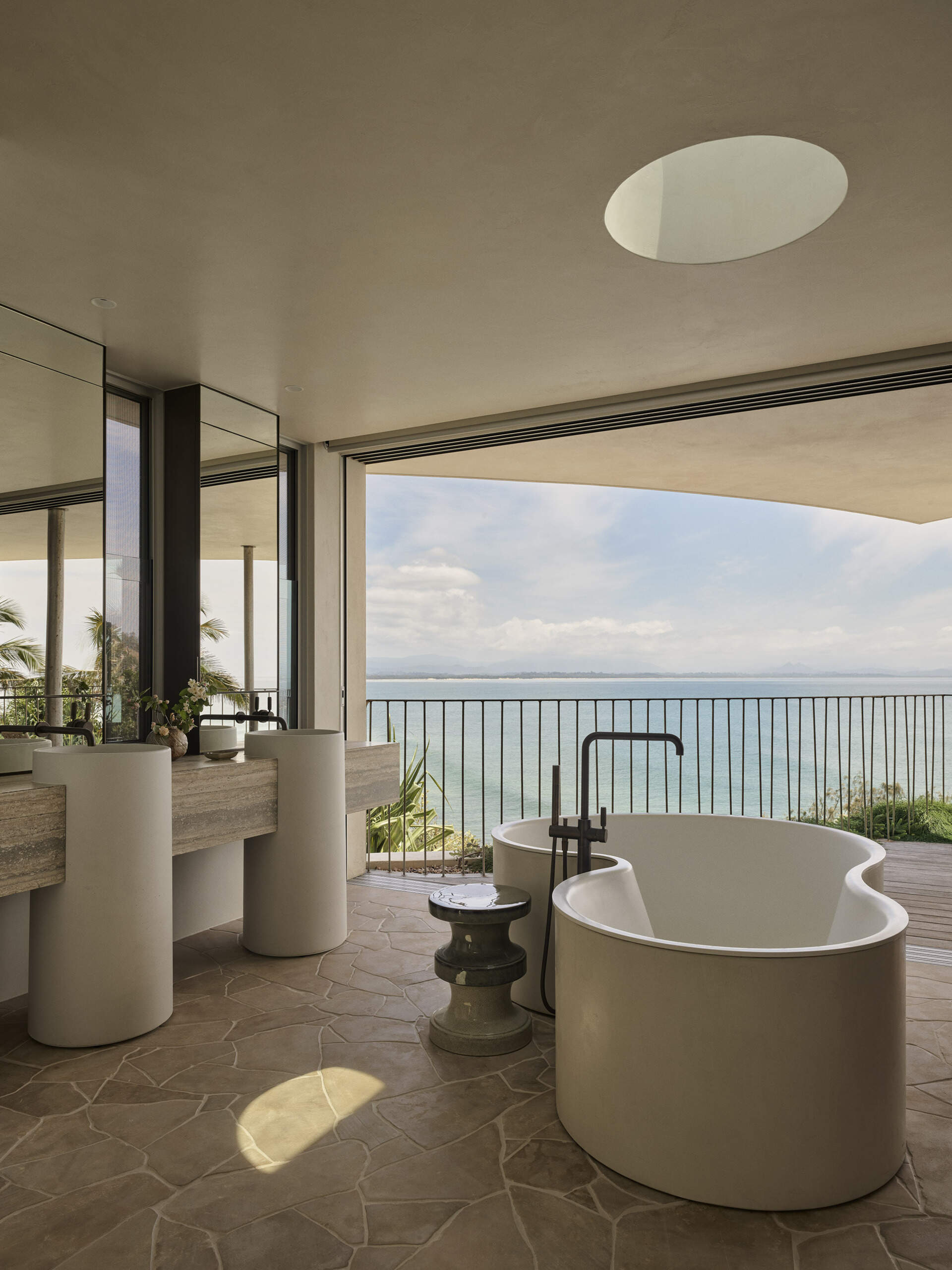 Inside this luxurious Byron Bay ensuite, an organically shaped Agape bath, curved shower and expansive glazing create a beautiful space overlooking the surrounding coastal landscape.