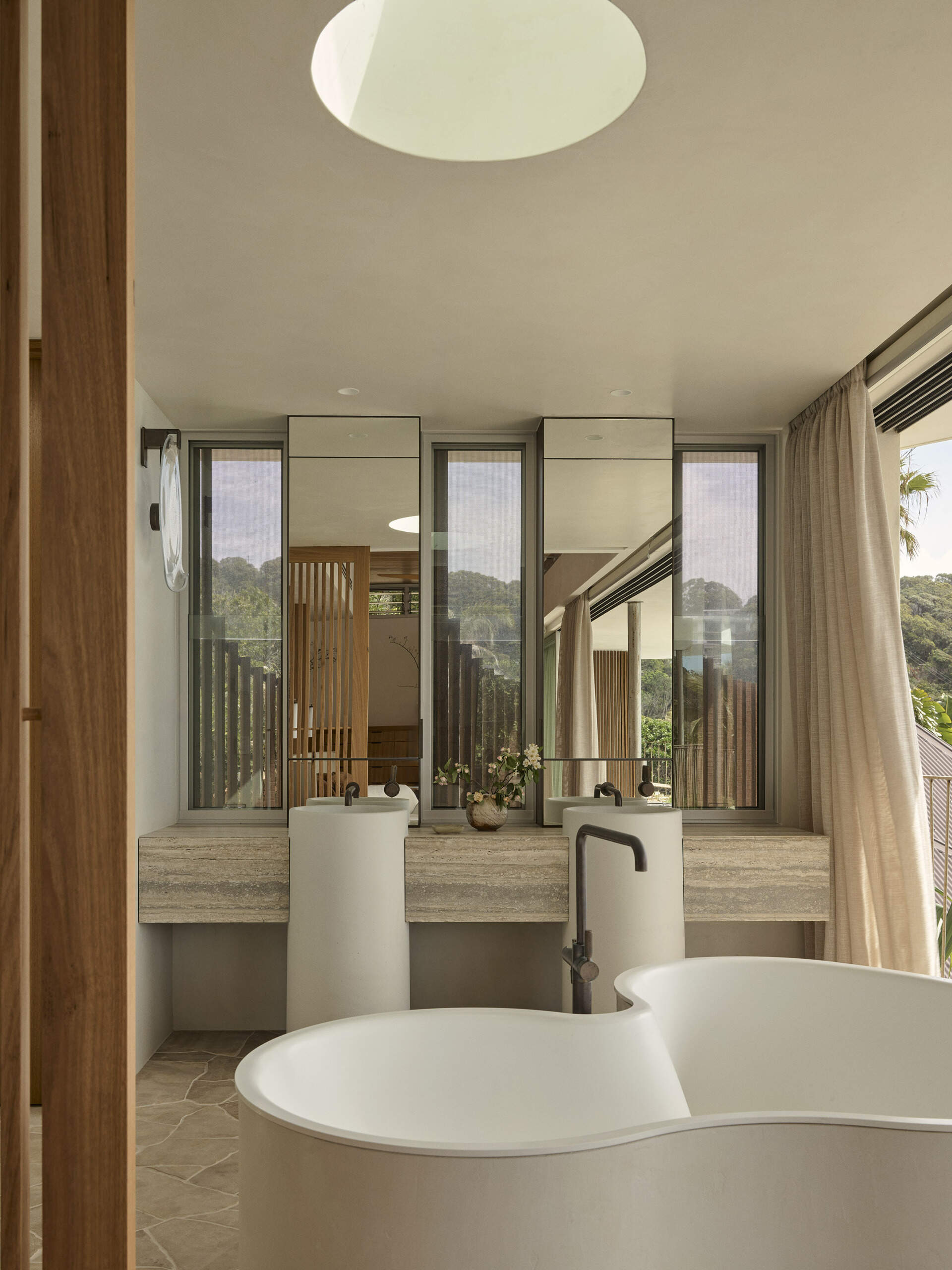 Inside this luxurious Byron Bay ensuite, an organically shaped Agape bath, curved shower and expansive glazing create a beautiful space overlooking the surrounding coastal landscape.