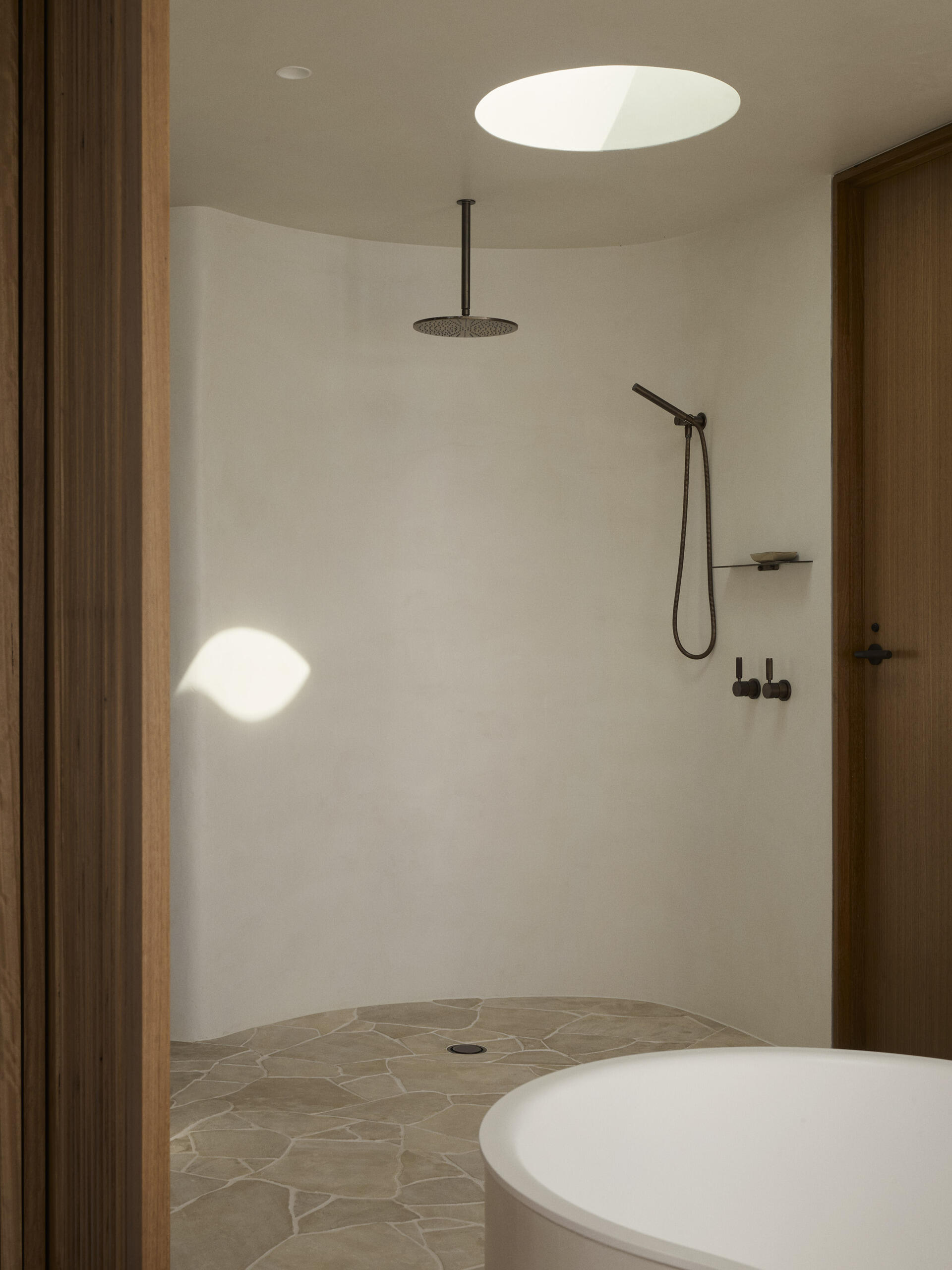 Inside this luxurious Byron Bay ensuite, an organically shaped Agape bath, curved shower and expansive glazing create a beautiful space overlooking the surrounding coastal landscape.