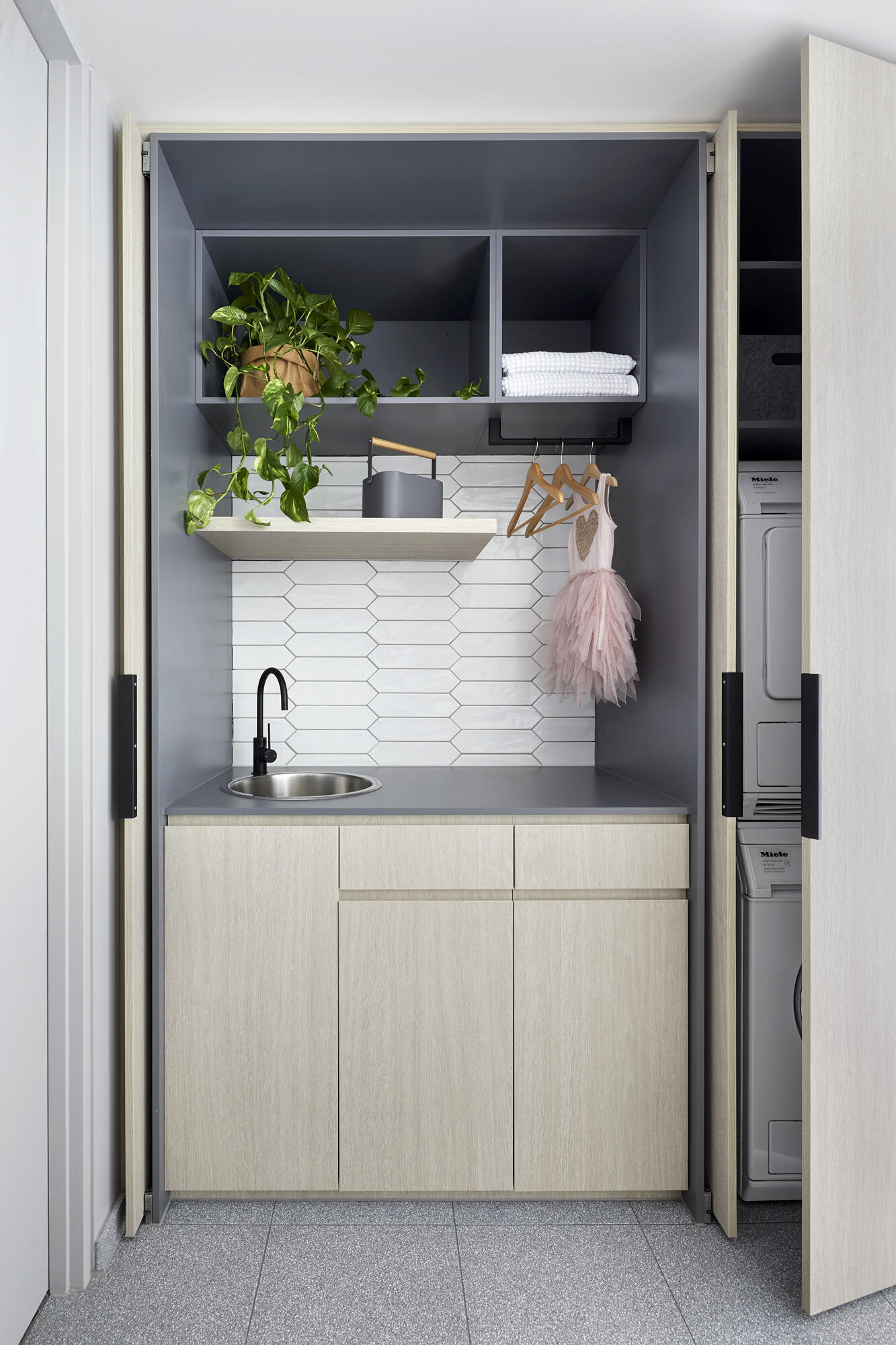 White picket tiles, hidden laundry storage, and a shower overlooking a tiny garden make this compact bathroom feel beautifully open.