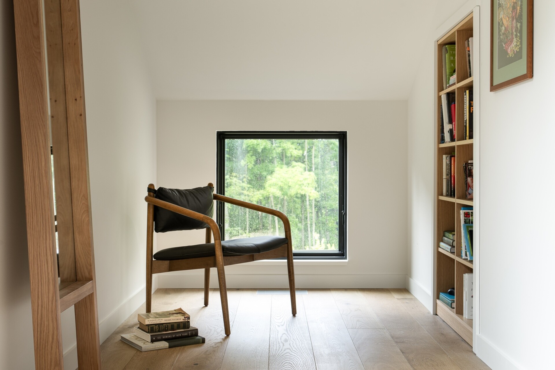 This primary bedroom moves away from the scale of the main gathering spaces, offering a more intimate interior within the larger house. Lighter wood and natural light continue the material palette used throughout the residence.

A nook within the bedroom has been transformed into a reading corner with a built-in bookshelf and a window.