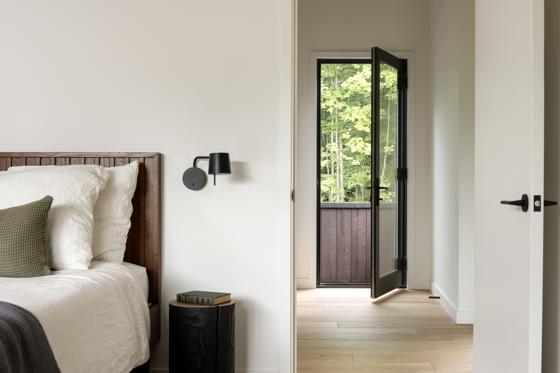 This primary bedroom moves away from the scale of the main gathering spaces, offering a more intimate interior within the larger house. Lighter wood and natural light continue the material palette used throughout the residence.

A nook within the bedroom has been transformed into a reading corner with a built-in bookshelf and a window.