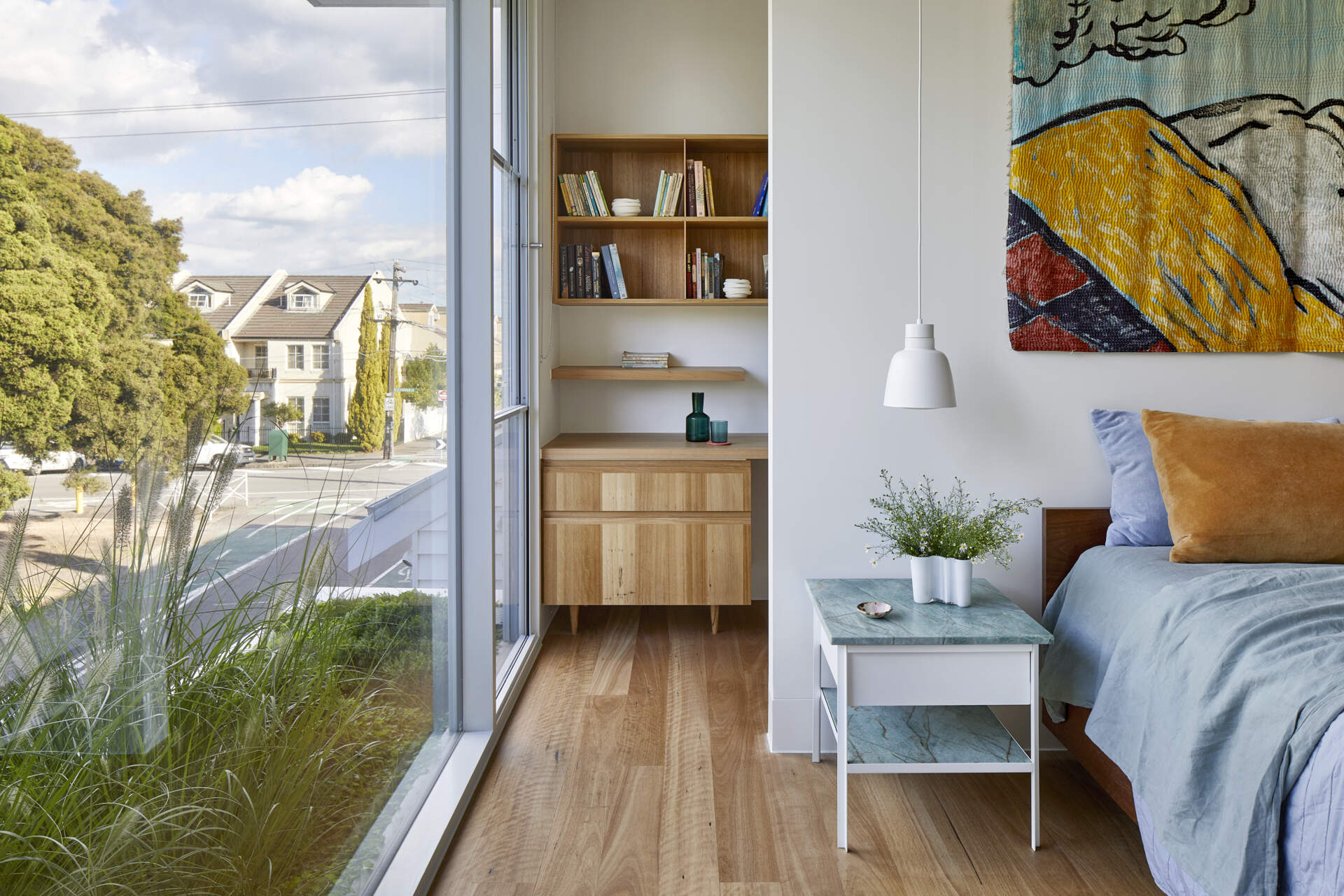 The main bedroom features a floor-to-ceiling window looking directly towards mature trees, and a hidden home office.