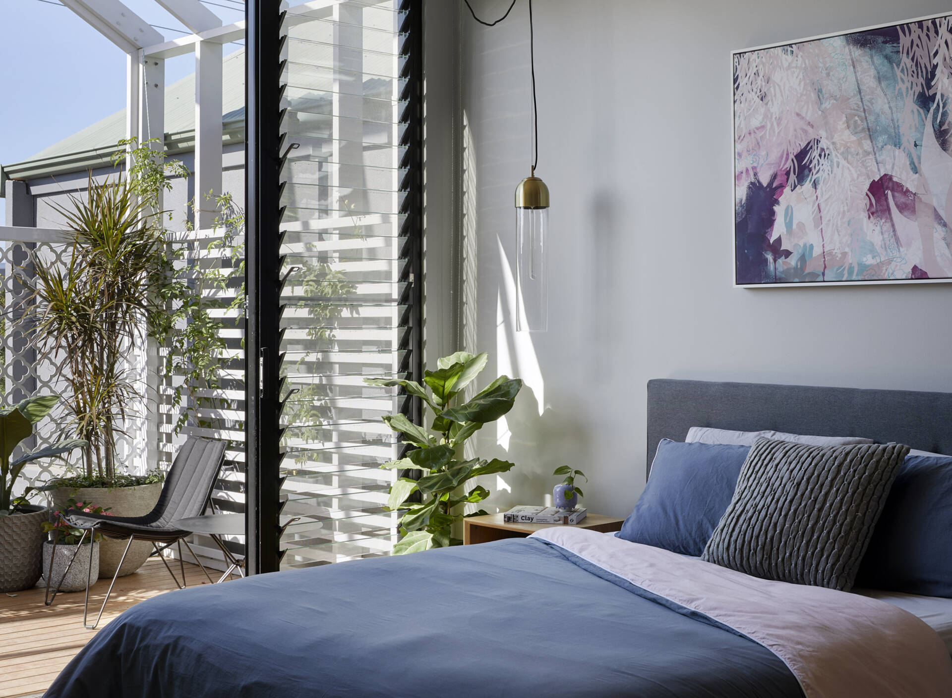 An upstairs bedroom opens to a balcony with louvre windows that keep fresh air flowing through this modern Australian home.