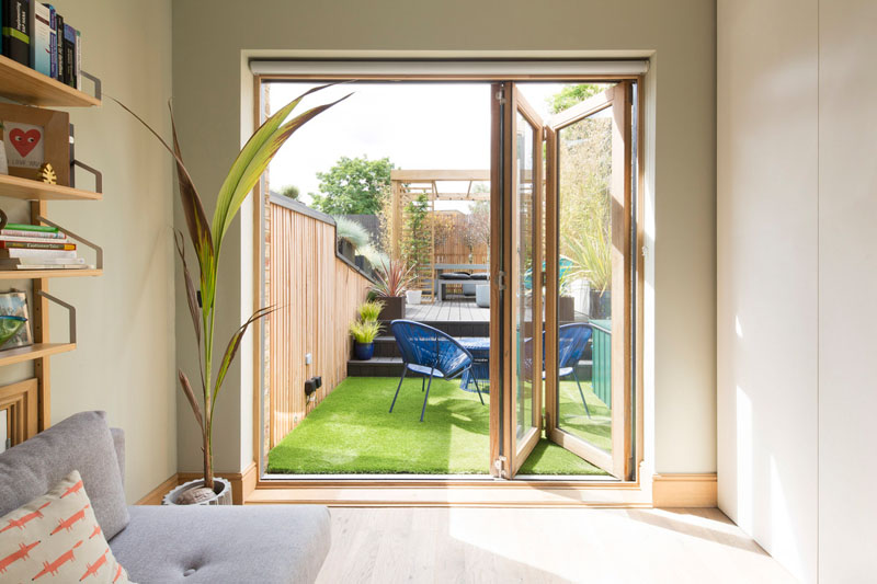 Wood-framed folding glass doors open this guest bedroom directly onto the yard, creating an easy connection between the interior and outdoor space.