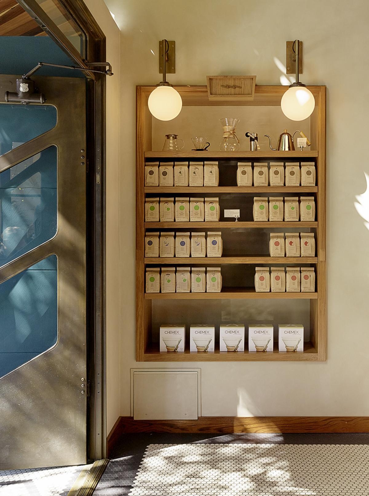 Step inside a bright warehouse café where marble, teak, plaster, and brass soften the industrial shell through custom craftsmanship and timeless materials.