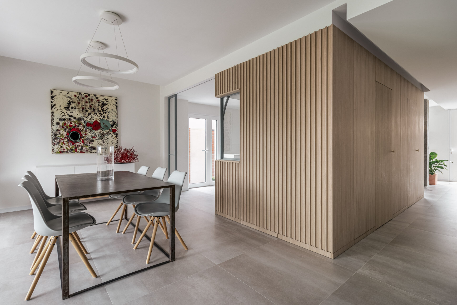 A long industrial-style dining table, Nordic chairs and garden views define the main dining area at the opposite end of this Madrid home.