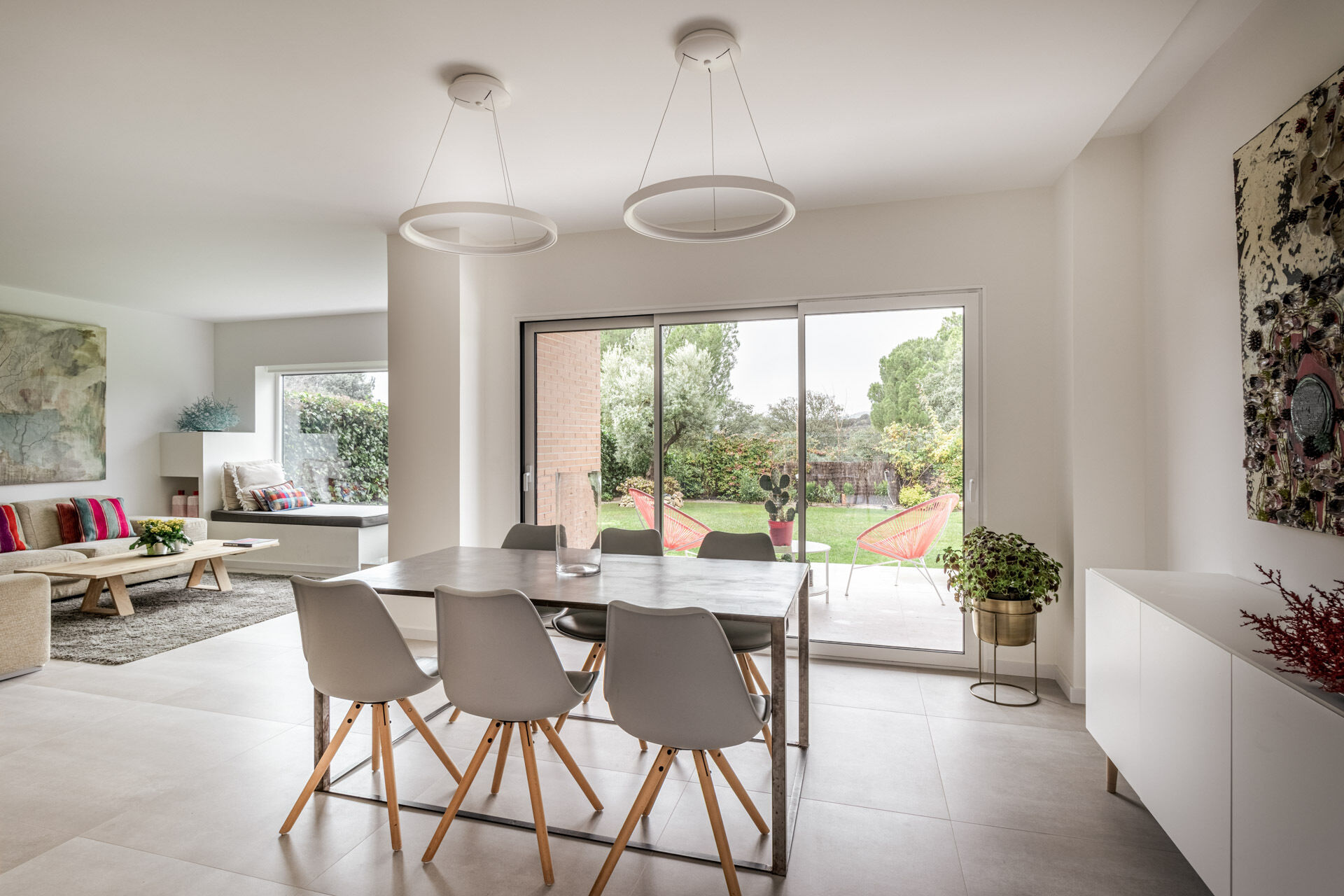 A long industrial-style dining table, Nordic chairs and garden views define the main dining area at the opposite end of this Madrid home.