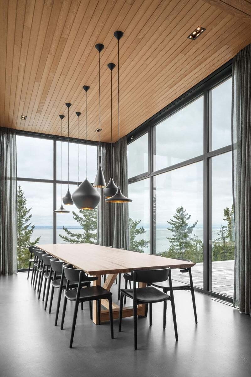 This glass-wrapped dining room extends away from the main house toward the horizon, with windows on three sides framing expansive views of the St. Lawrence River.