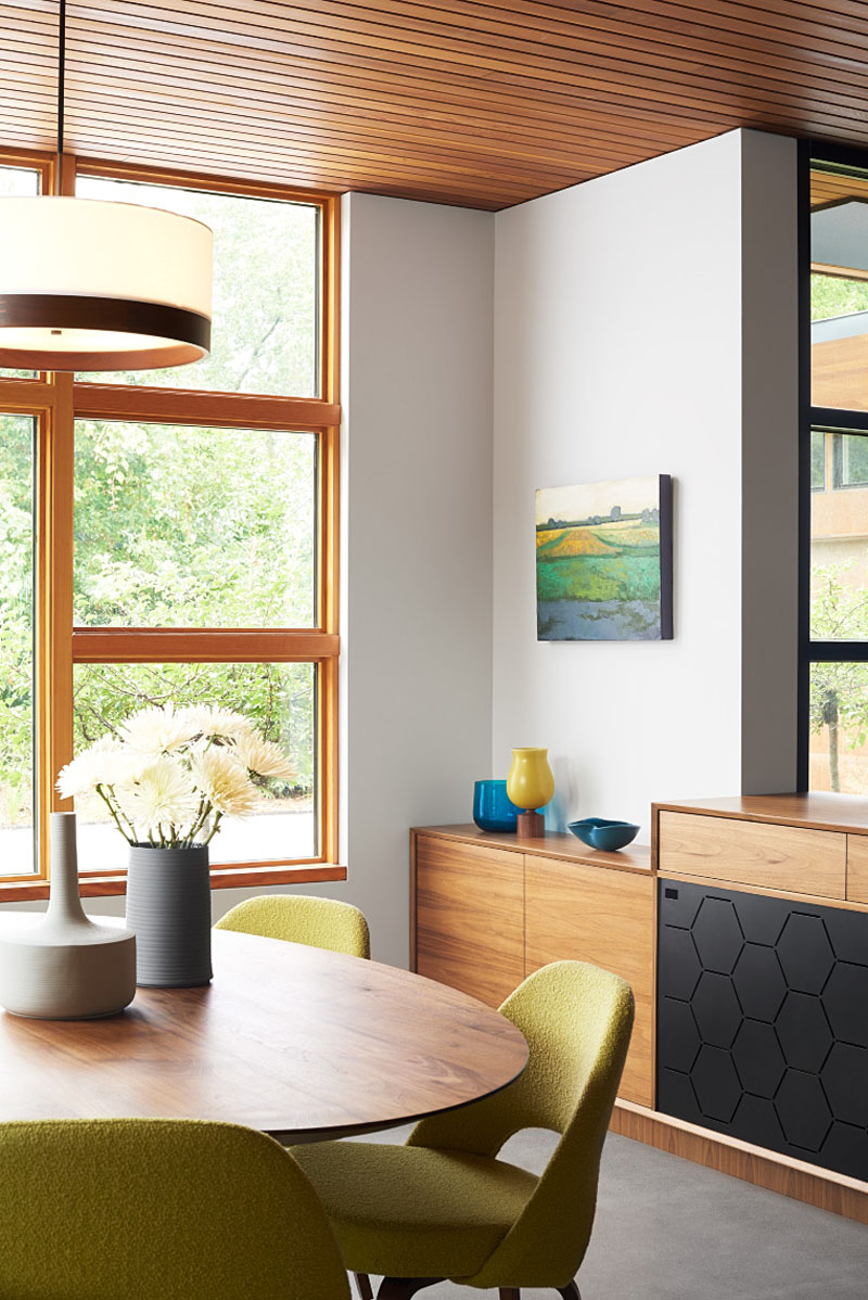 Wood cabinetry, a timber ceiling and wood dining table create a warm dining room in this modern ranch house designed by Strand Design.