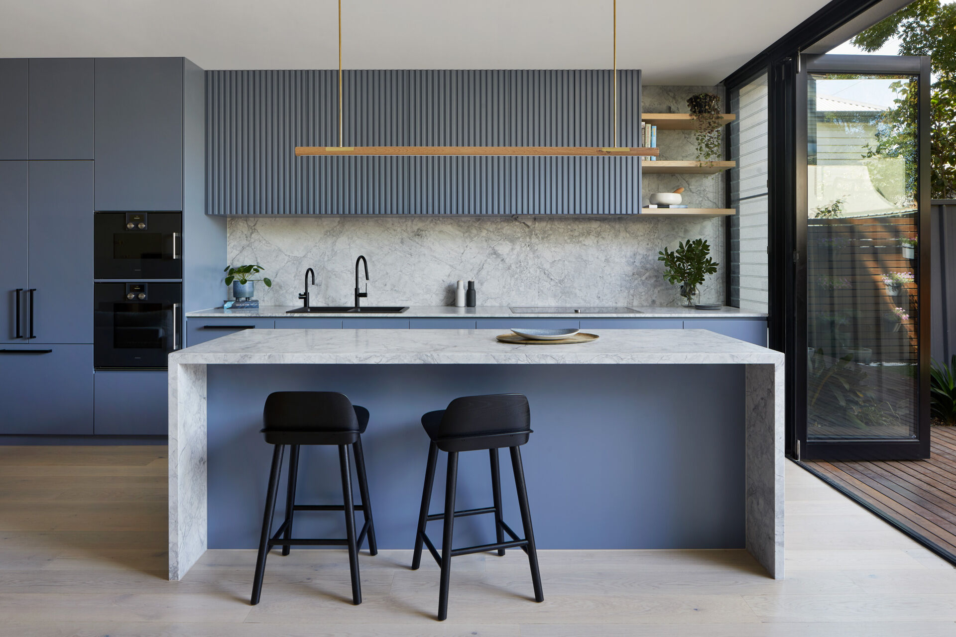 Soft blue kitchen cabinets paired with Super White marble create a bright, modern kitchen in this renovated Port Melbourne workers cottage.