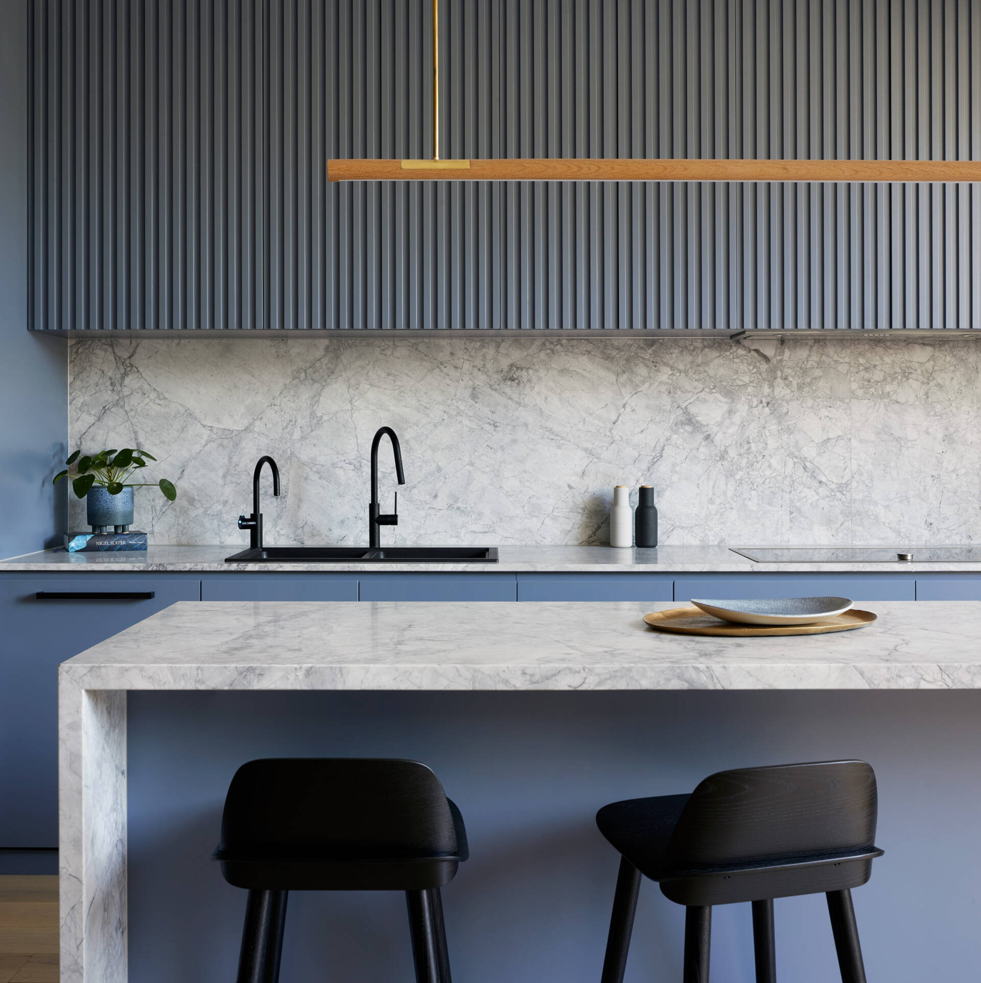Soft blue kitchen cabinets paired with Super White marble create a bright, modern kitchen in this renovated Port Melbourne workers cottage.