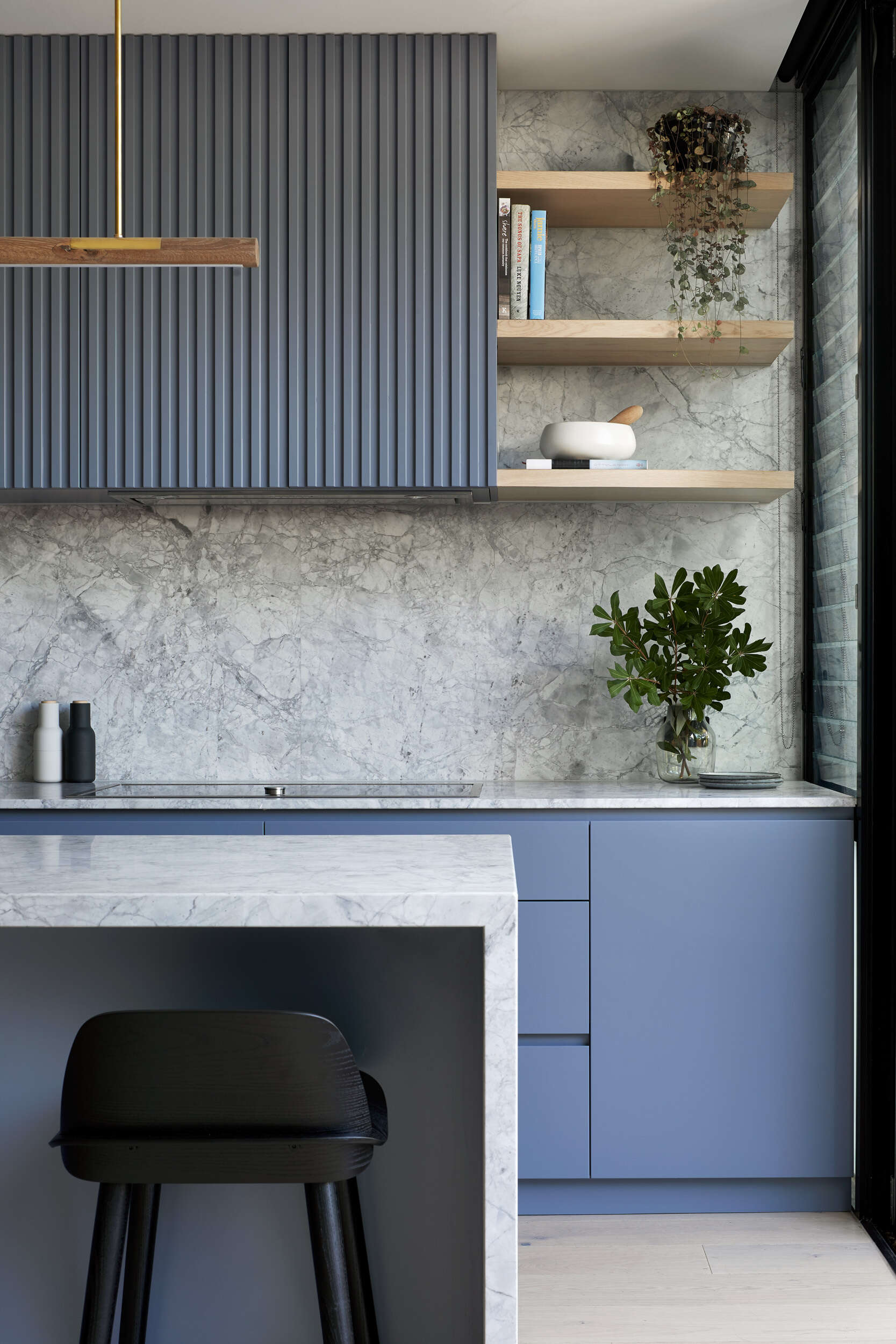 Soft blue kitchen cabinets paired with Super White marble create a bright, modern kitchen in this renovated Port Melbourne workers cottage.