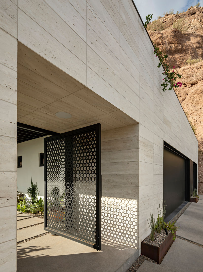 A custom pivot gate by Bang Bang Designs introduces the Red Rocks residence in Phoenix with a decorative hexagonal pattern. Beyond it, a covered patio creates a welcoming outdoor arrival.