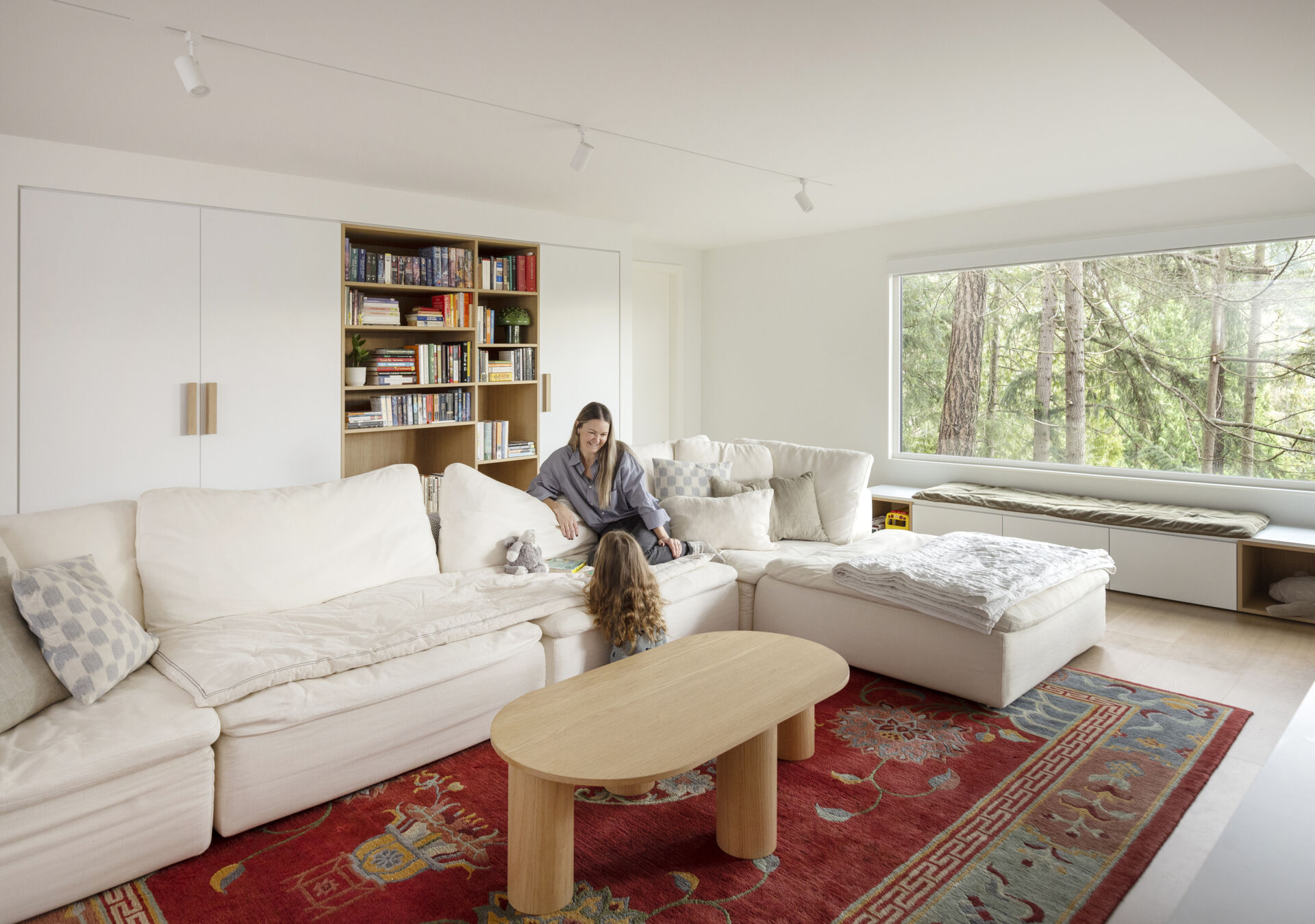 Enlarged windows, built-in shelving and storage benches transform the lower-level family room of this West Vancouver home into a bright space overlooking the surrounding trees.
