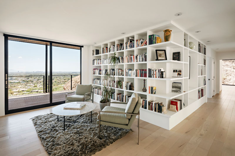 Maple wood floors and white open shelving give the library at this Phoenix residence a bright, warm interior. The restrained palette keeps attention on the architecture and desert views.