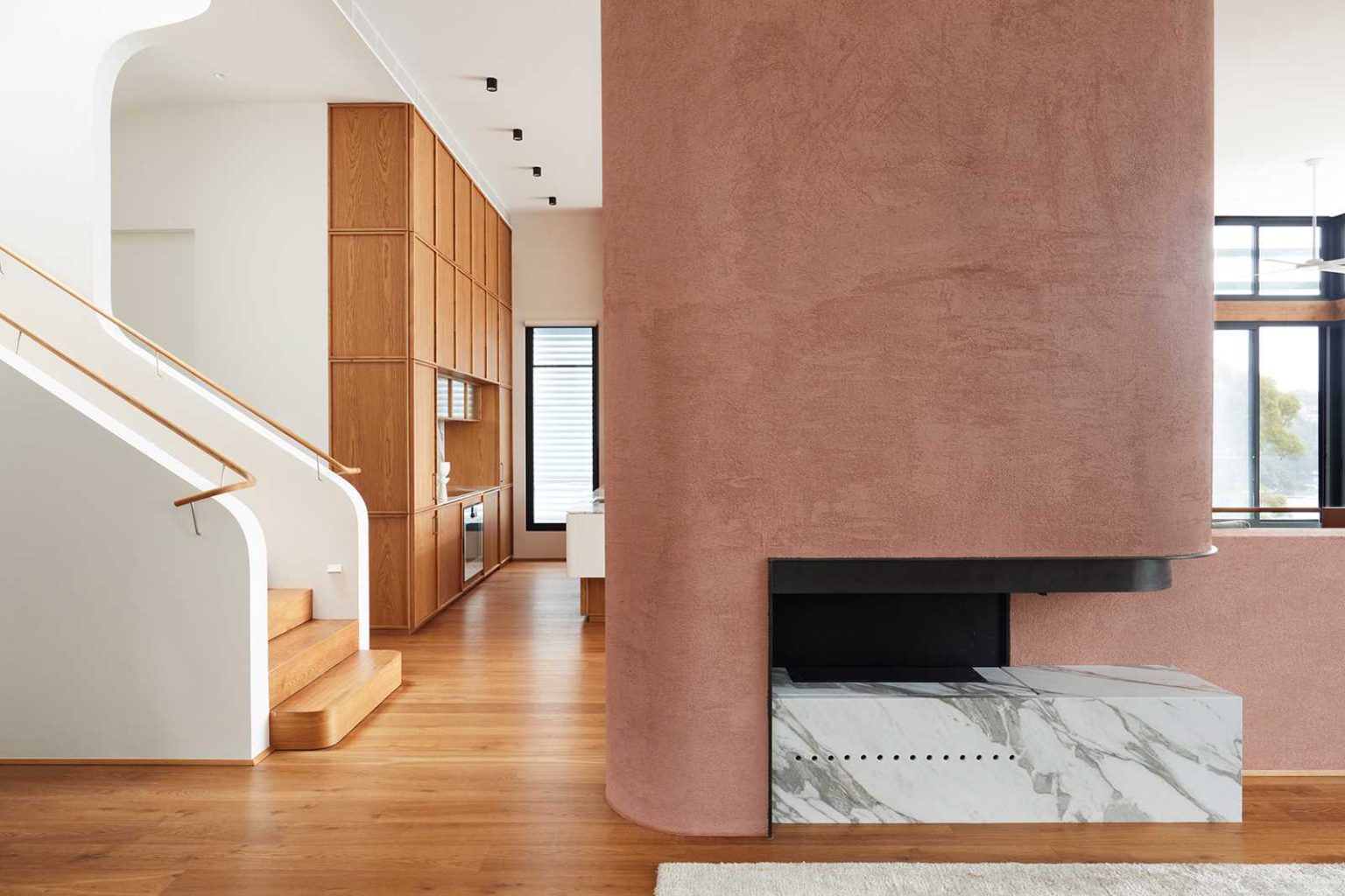 A fireplace sits between the living, kitchen and dining areas inside Earth-Ship, creating a warm architectural feature within Luigi Rosselli Architects' Sydney renovation.