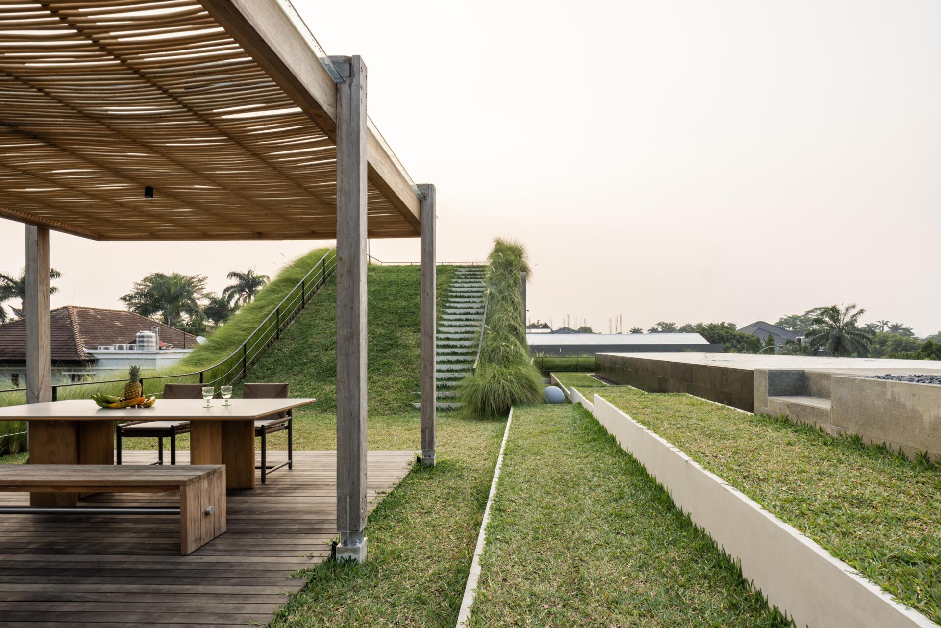 The second floor of Split Mass Residence opens toward outdoor living, with a BBQ area, sunken outdoor living room, swimming pool, gym and bathroom.