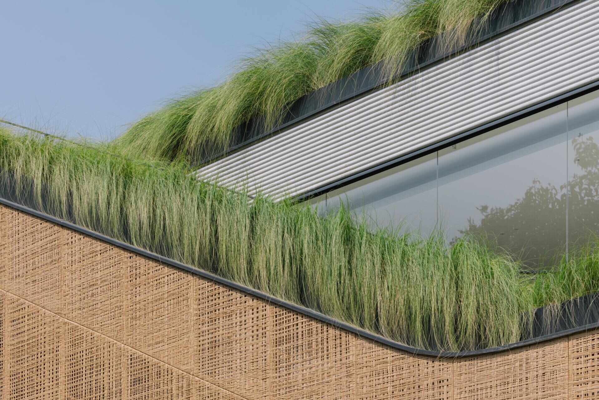 Explore the exterior of Split Mass Residence, where split architectural volumes, rounded corners, bamboo-textured concrete and woven recycled PET rattan screens shape this Indonesian home.