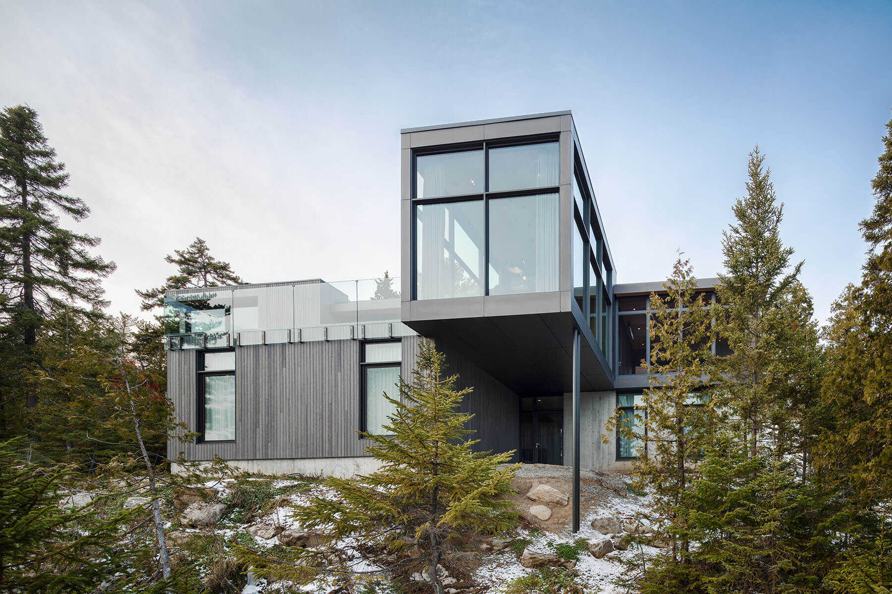 Long Horizontals by Thellend Fortin Architectes is a modern Québec house built on a steep rocky site overlooking the St. Lawrence River, with long horizontal forms, concrete, light wood and expansive glass opening the home toward the horizon.