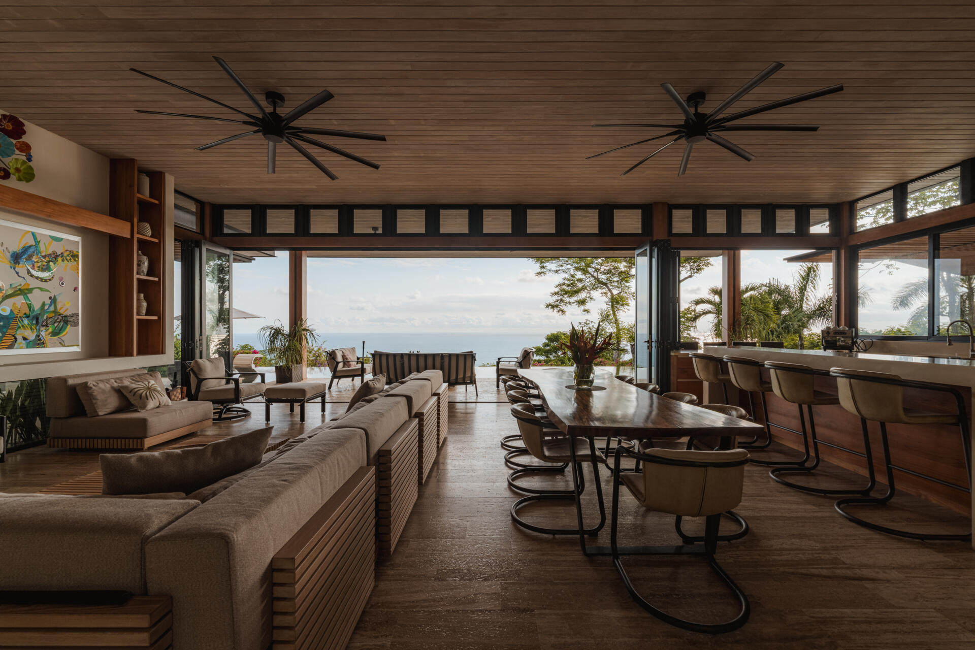 A natural-edge dining table, warm timber and colorful artwork bring character to the open dining area at this tropical Costa Rica home overlooking the Pacific.