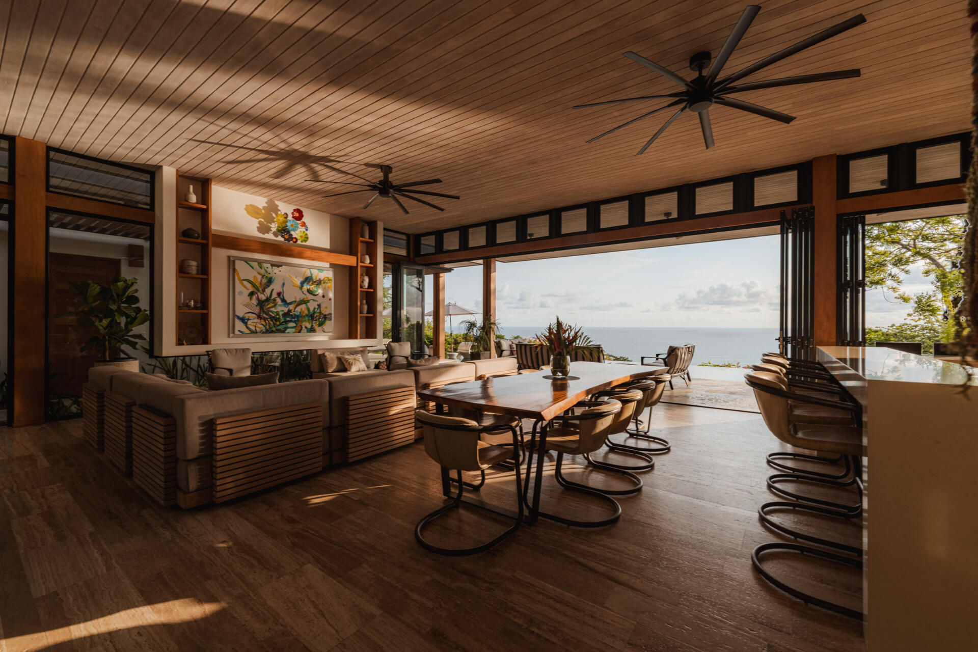 A natural-edge dining table, warm timber and colorful artwork bring character to the open dining area at this tropical Costa Rica home overlooking the Pacific.