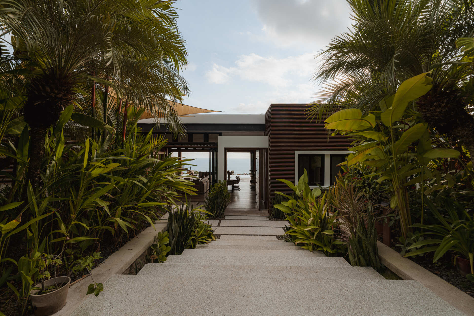 Tierra y Mar House in Mal País, Costa Rica, by Álvarez Arquitectos features layered architectural platforms, a wave-inspired roof and an exterior bridge extending toward the forest canopy.