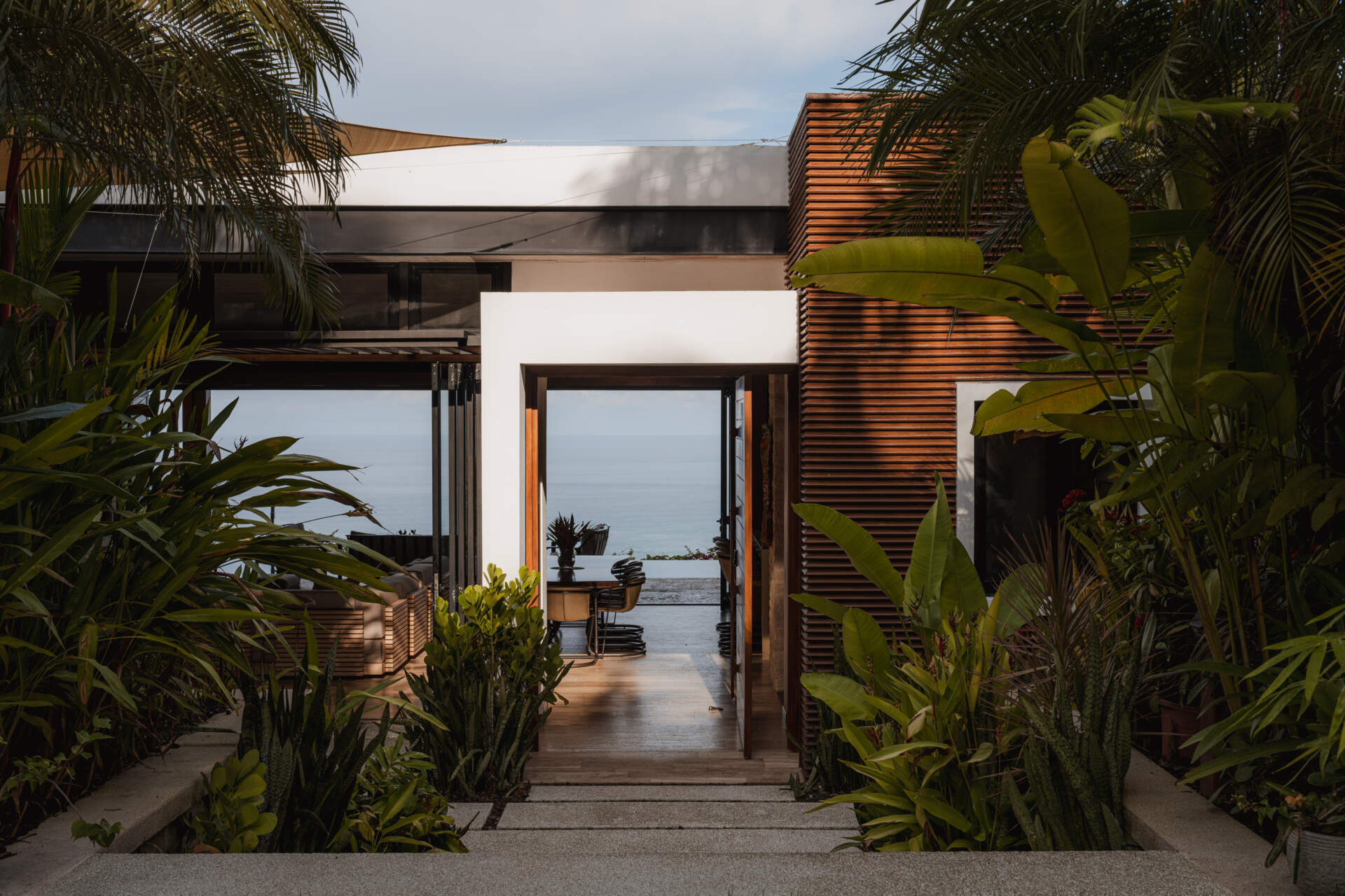 Tierra y Mar House in Mal País, Costa Rica, by Álvarez Arquitectos features layered architectural platforms, a wave-inspired roof and an exterior bridge extending toward the forest canopy.