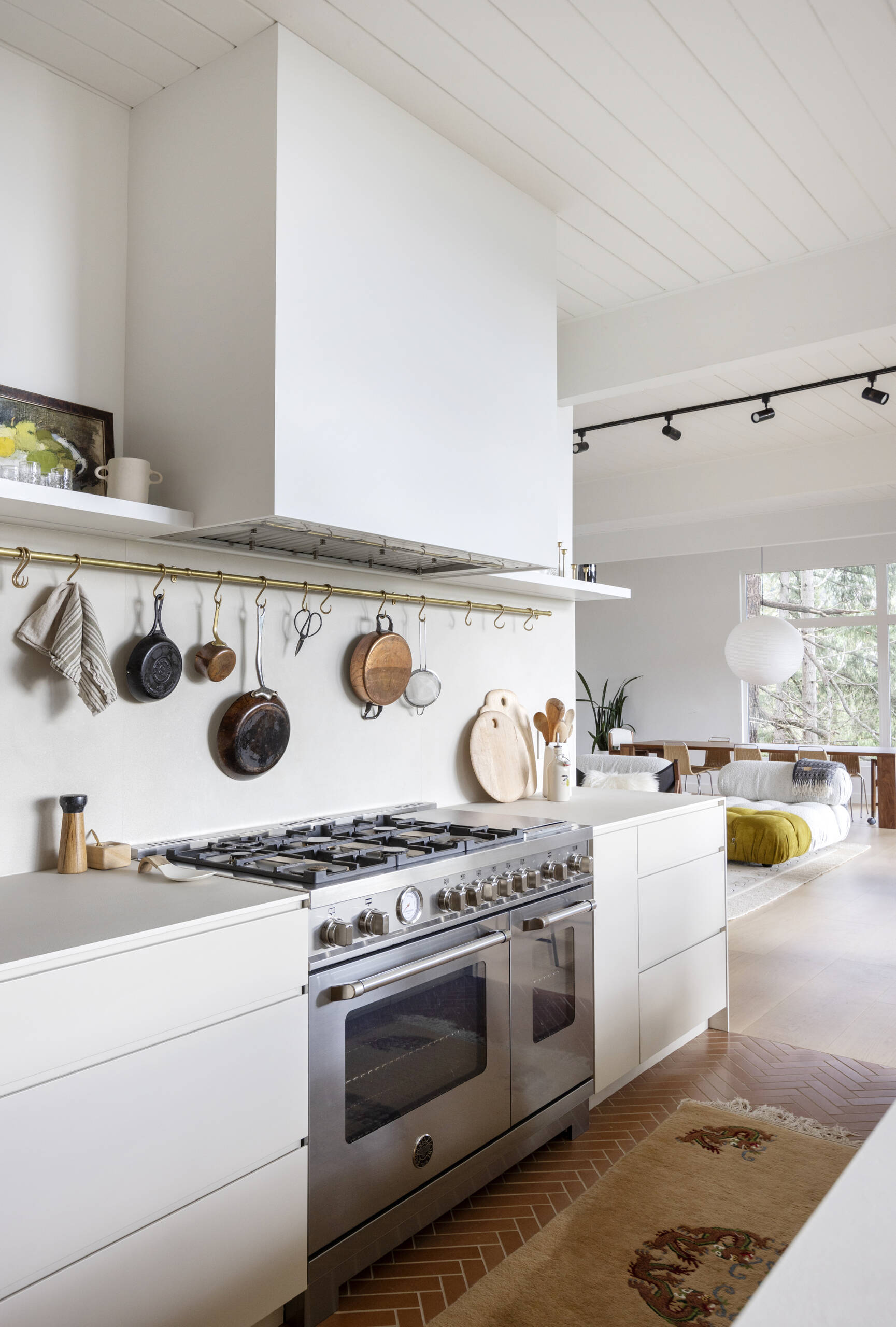 See how a 1961 mid-century kitchen was transformed with white oak cabinetry, a hidden pantry, coffee station, breakfast bar and oversized island, creating a warm and functional space for cooking and family gatherings.