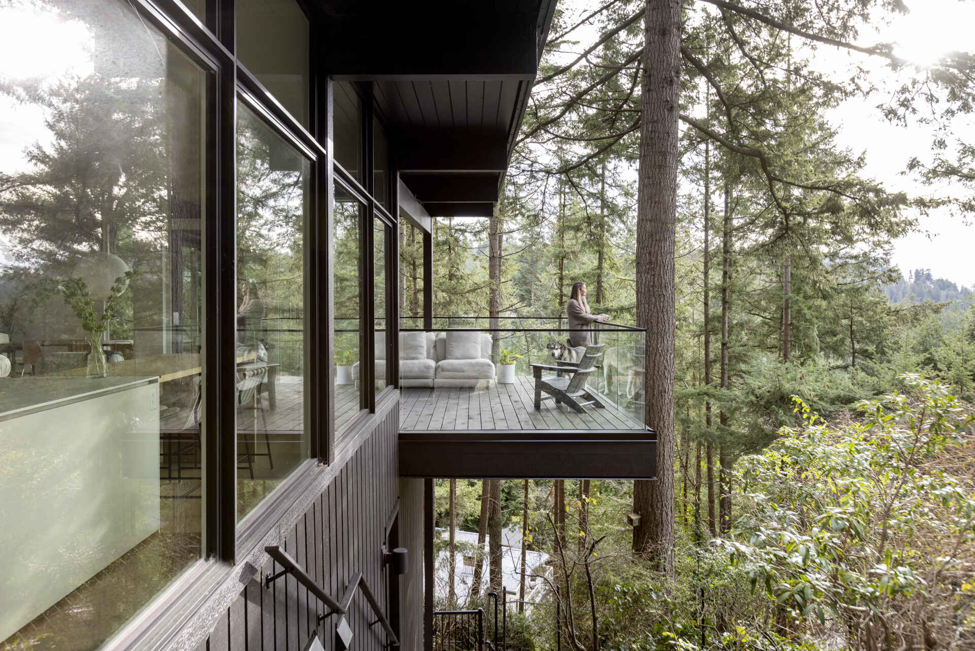This expanded cantilevered deck gives a West Vancouver mid-century home the feeling of another outdoor room, extending the living spaces toward the surrounding forest and views of Lions Bay.