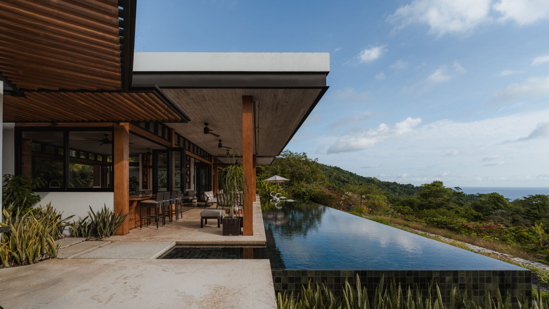 An infinity pool, covered outdoor living area and distant Pacific Ocean views create an inviting outdoor space at Tierra y Mar House in Mal País, Costa Rica.